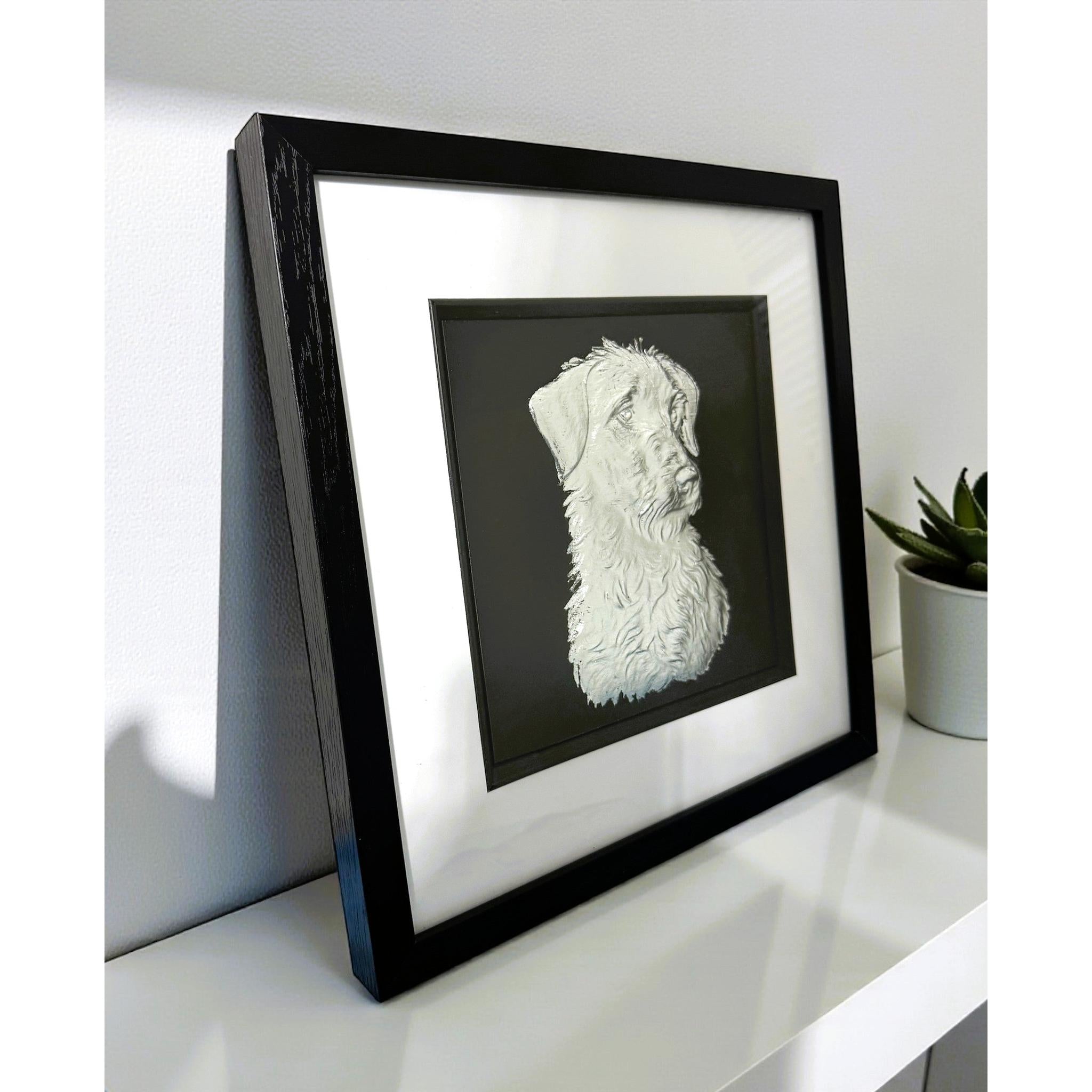 Lurcher silver leaf wall art photographed at an angle on a shelf with black frame and white mount