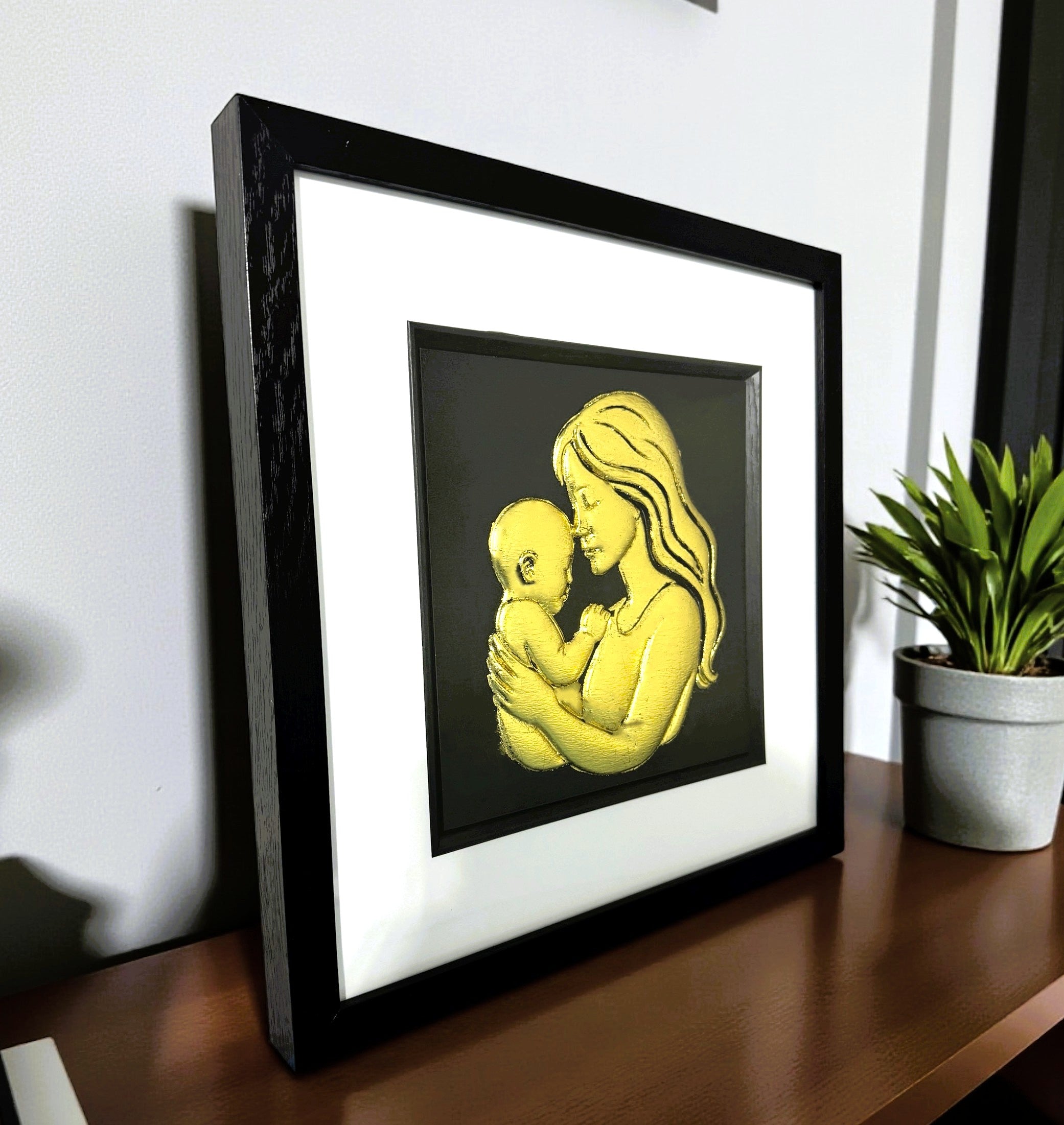 Framed mother and baby wall art displayed on a shelf in a modern interior