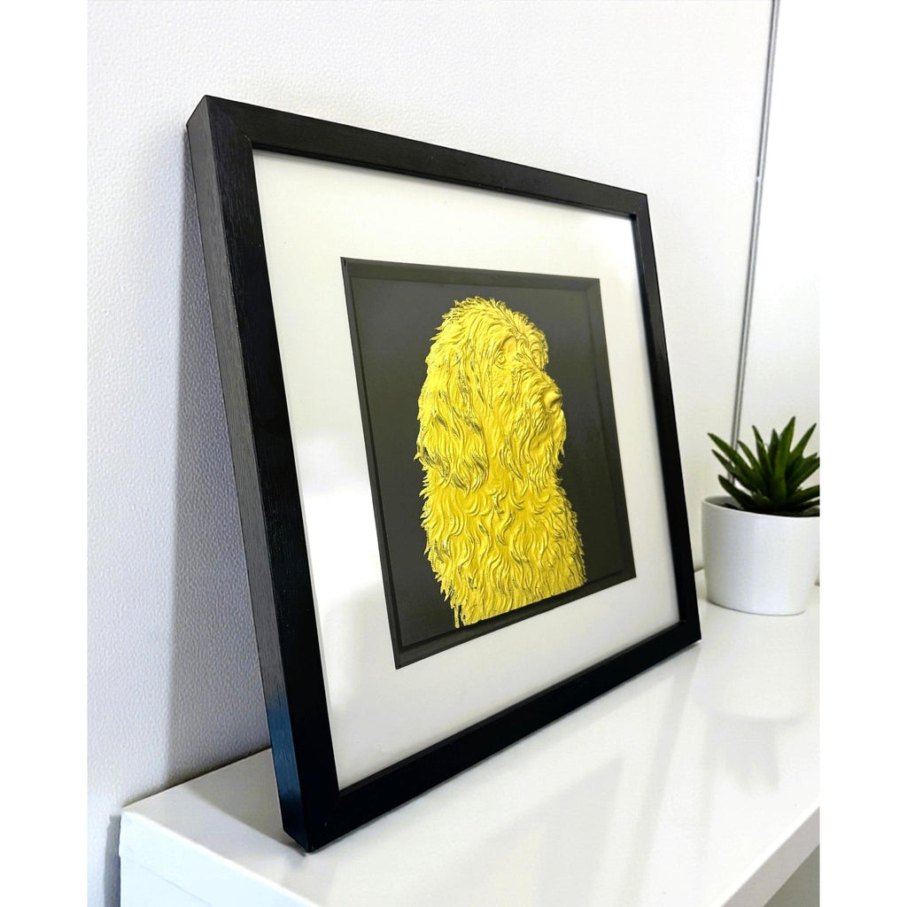 Otterhound gold leaf wall art photographed at an angle on a shelf with black frame white mount and black background