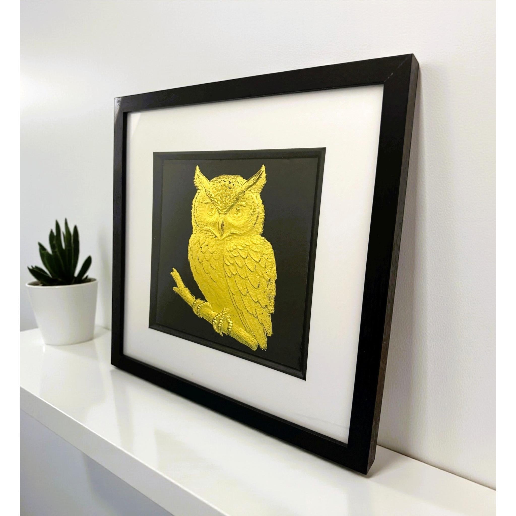 Gold leaf owl framed wall art on black background with white mount, angled shelf view