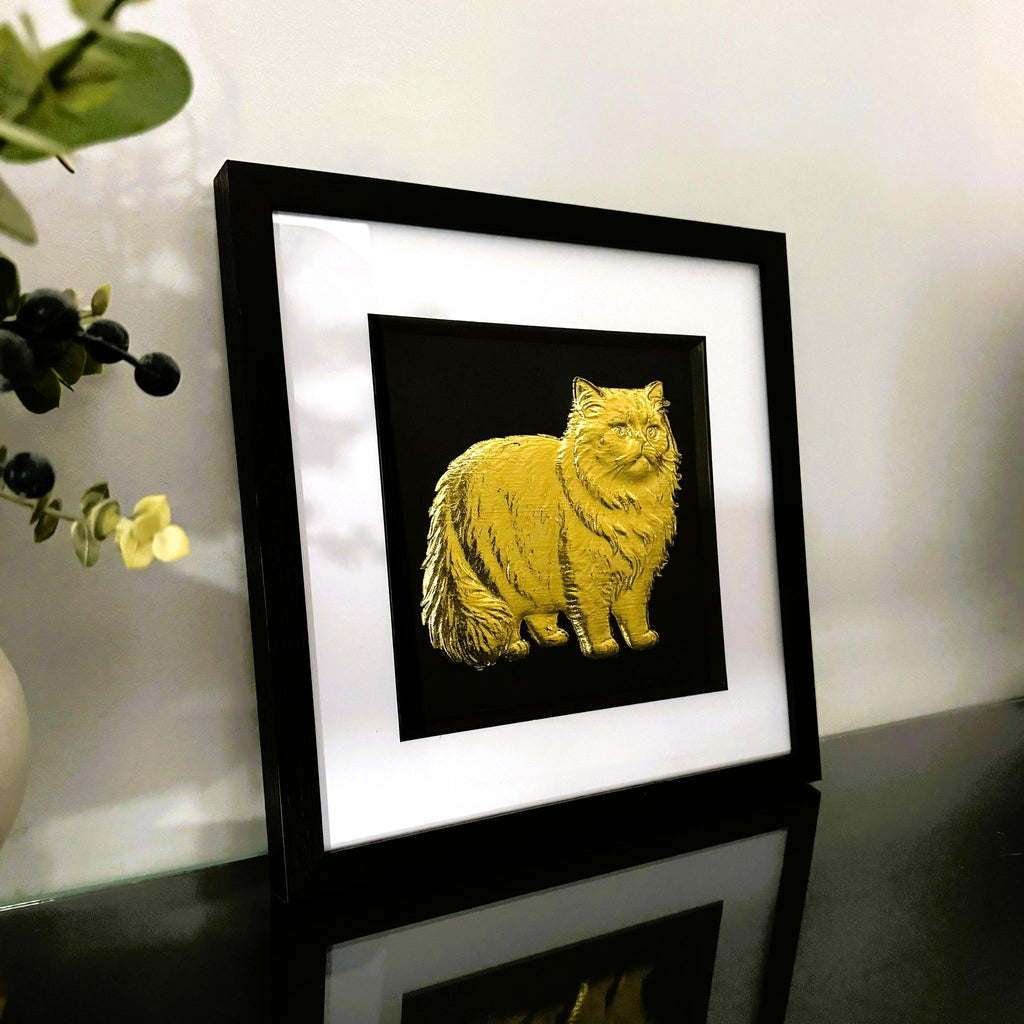 Persian cat gold leaf wall art displayed on desk surface in black frame with white mount
