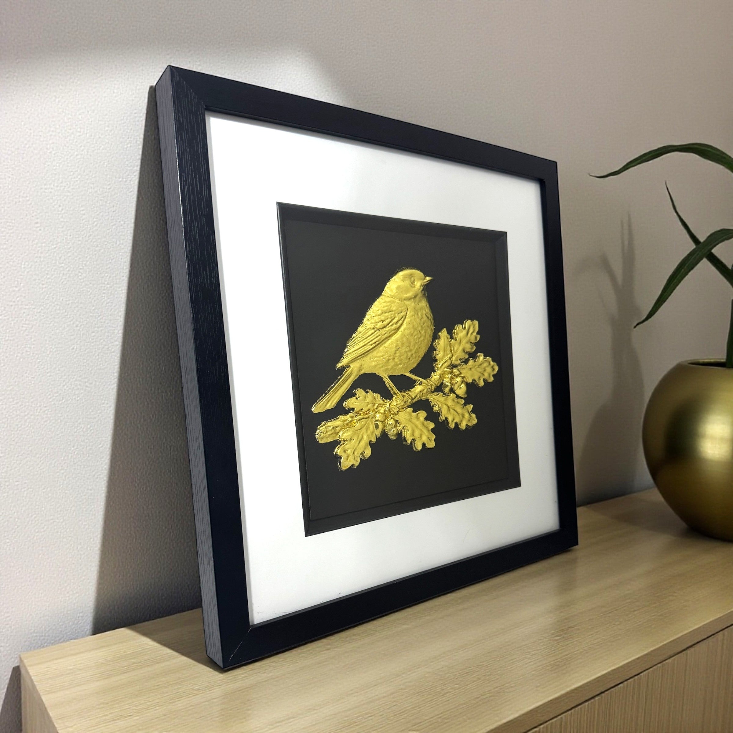 Gold leaf robin wall art on oak branch displayed on a sideboard in a modern home, framed