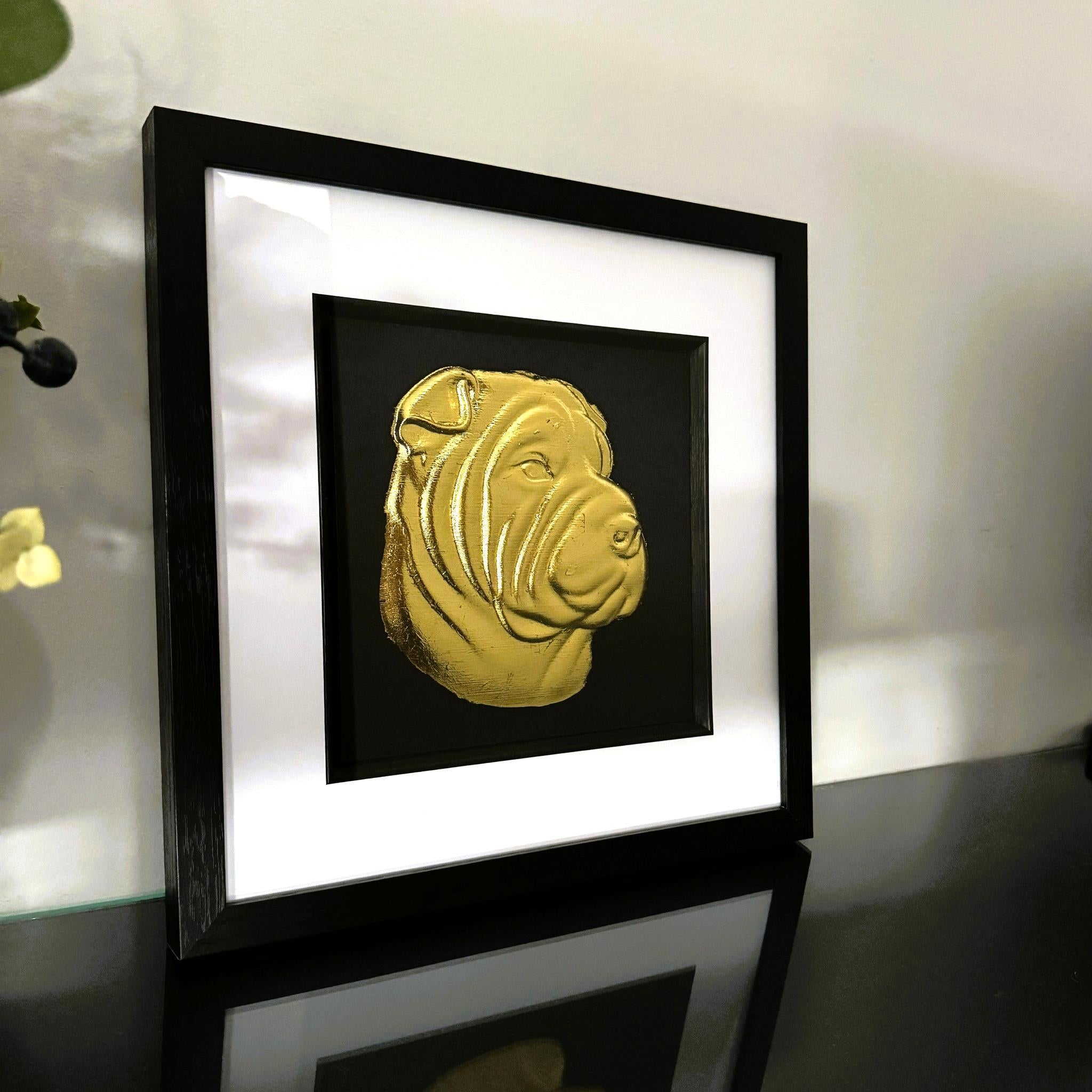 Shar Pei gold leaf wall art photographed at an angle on a reflective surface with black frame and white mount
