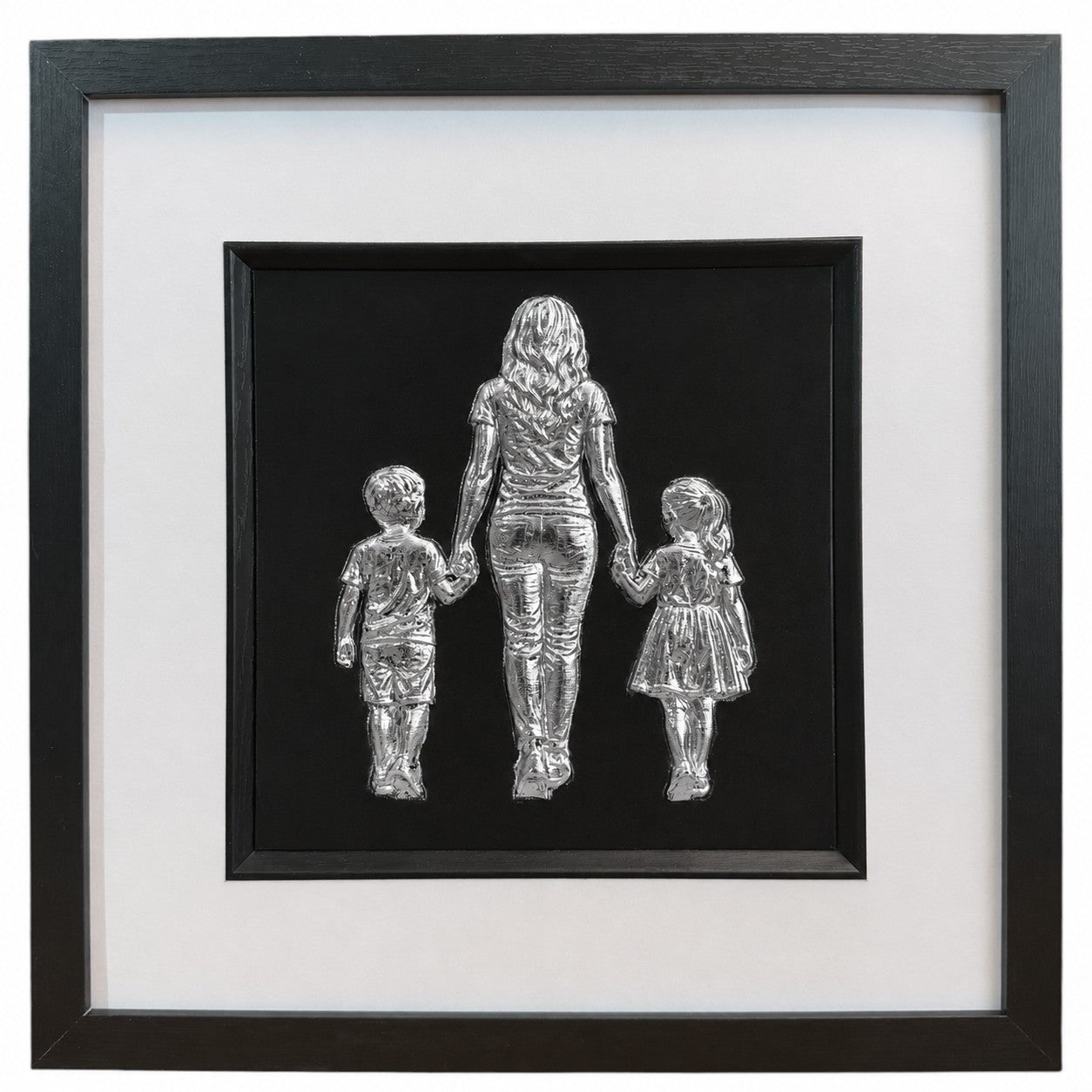 Mum, son and daughter framed wall art showing three sculpted figures walking hand in hand in silver leaf, set on a black background with white mount and black wooden frame