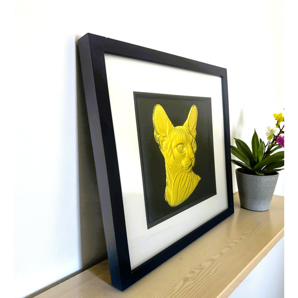 Sphynx cat gold leaf wall art shown at an angle on desk surface in black frame with white mount