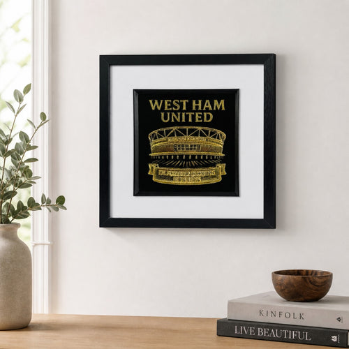 Lifestyle photo of West Ham United wall art displayed on a neutral wall above a wooden surface with home decor.