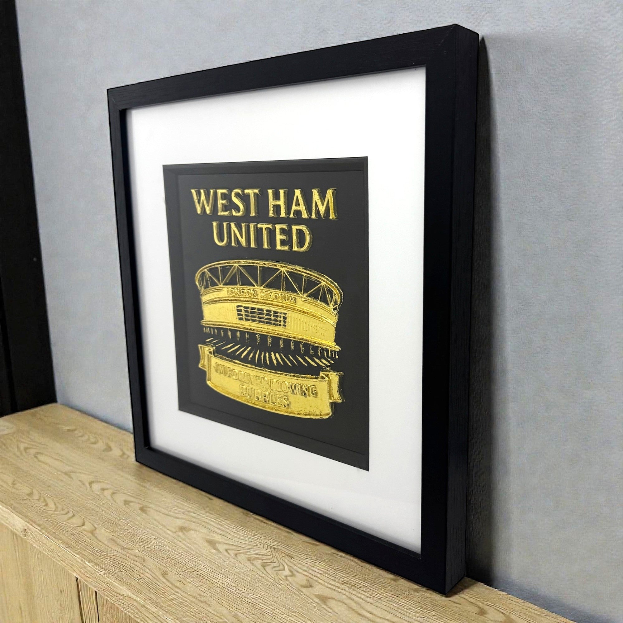 West Ham United football gift London Stadium wall art in gold leaf shown styled on a desk in black frame