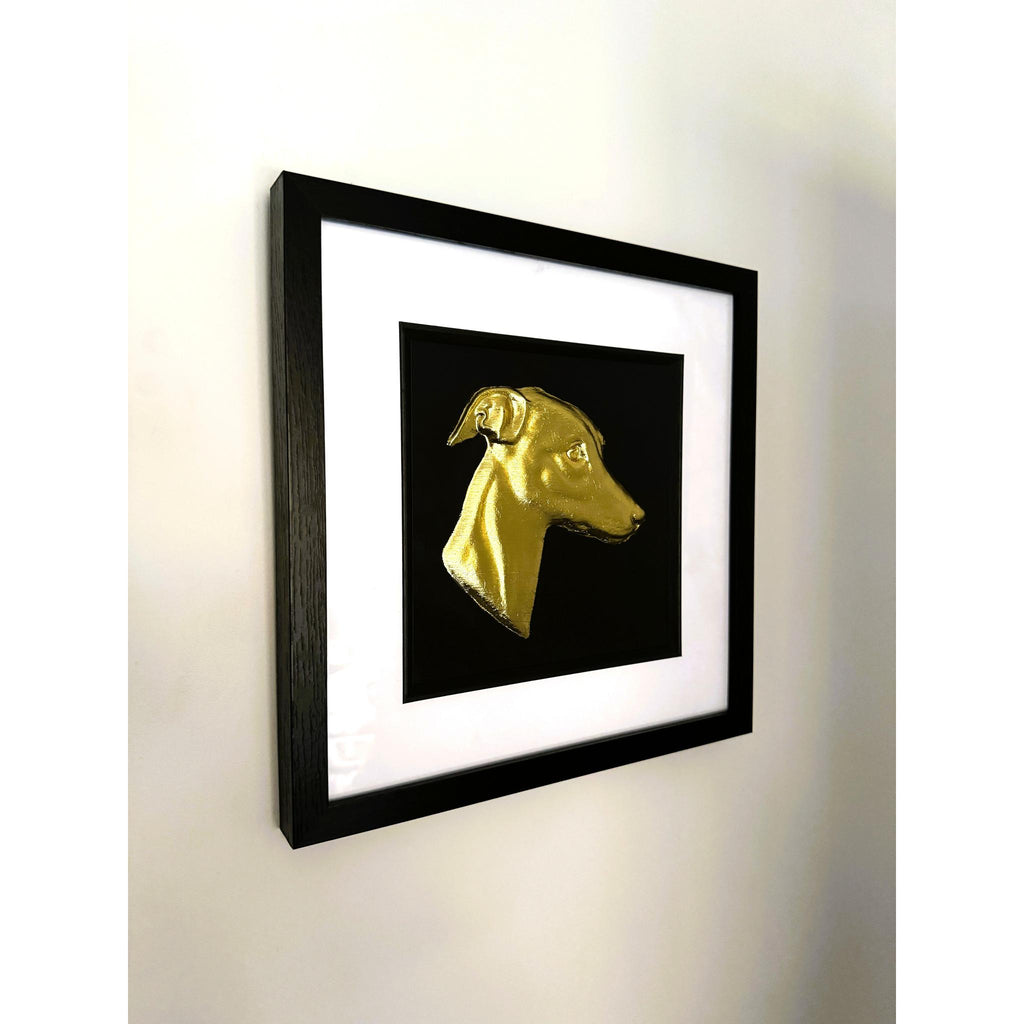 Gold leaf whippet wall art photographed at an angle showing black frame and white mount