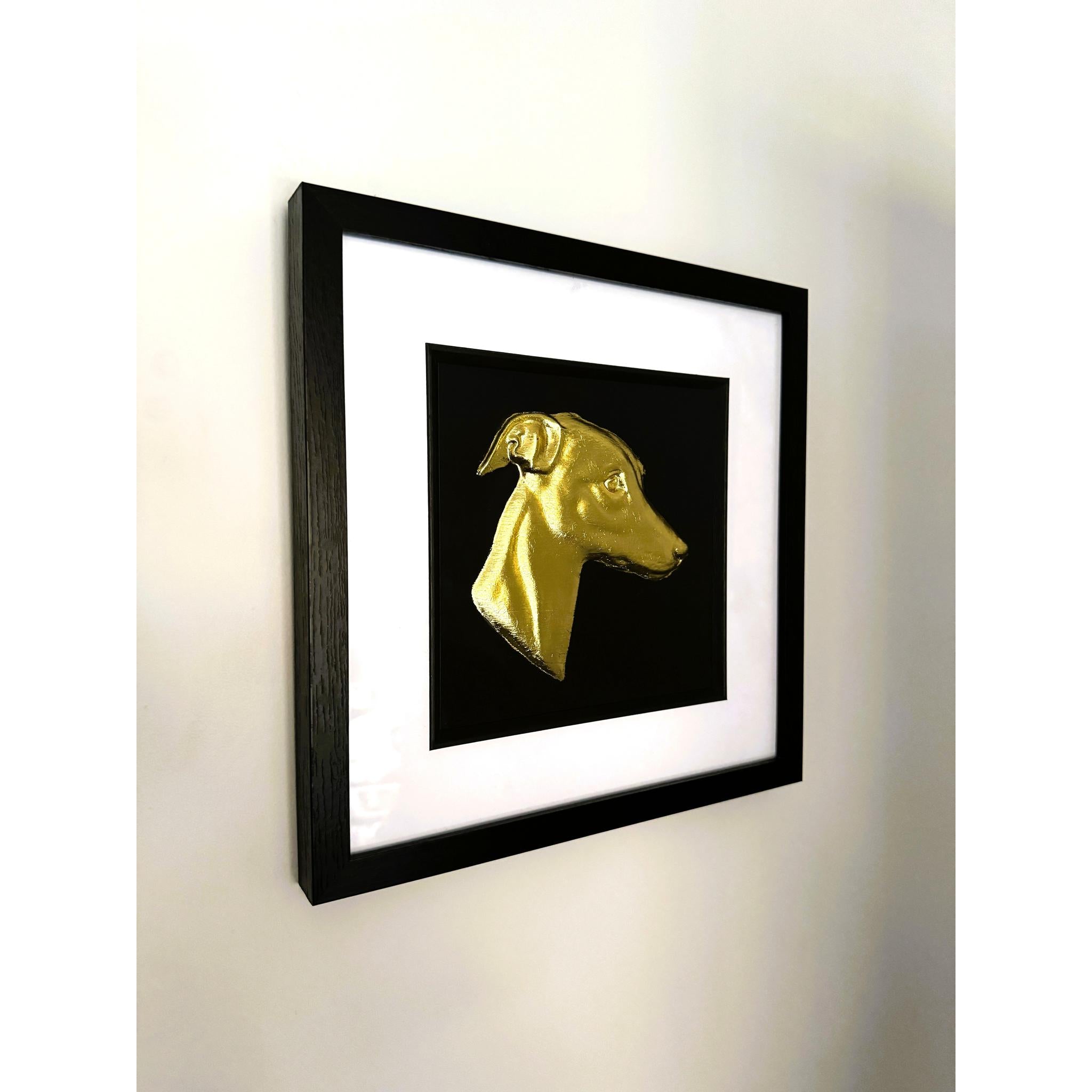 Gold leaf whippet wall art photographed at an angle showing black frame and white mount