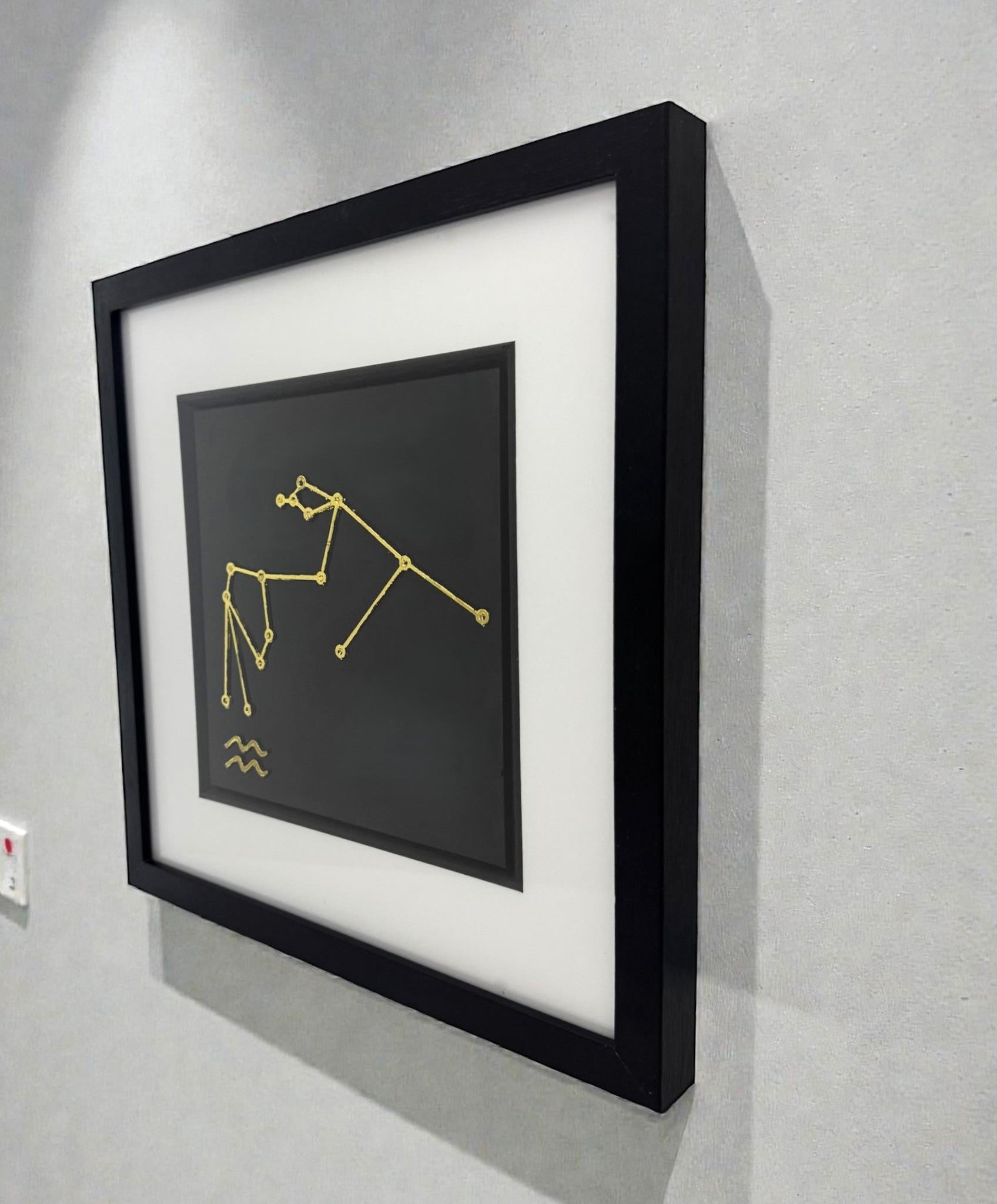 Framed gold Aquarius constellation wall art displayed on a wall, black frame with white mount and Aquarius star pattern