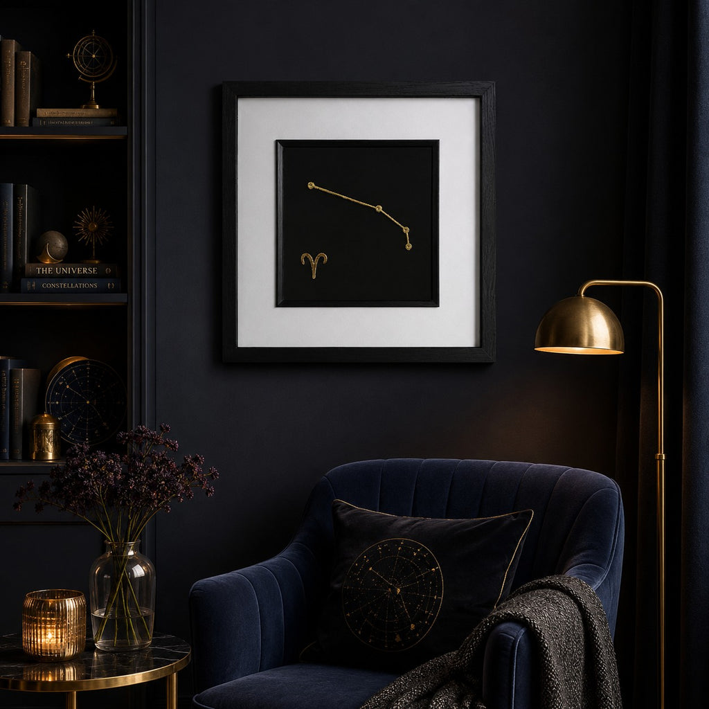 Aries zodiac constellation framed wall art in gold displayed on a dark wall with celestial decor, velvet chair, warm lighting and gold accents.