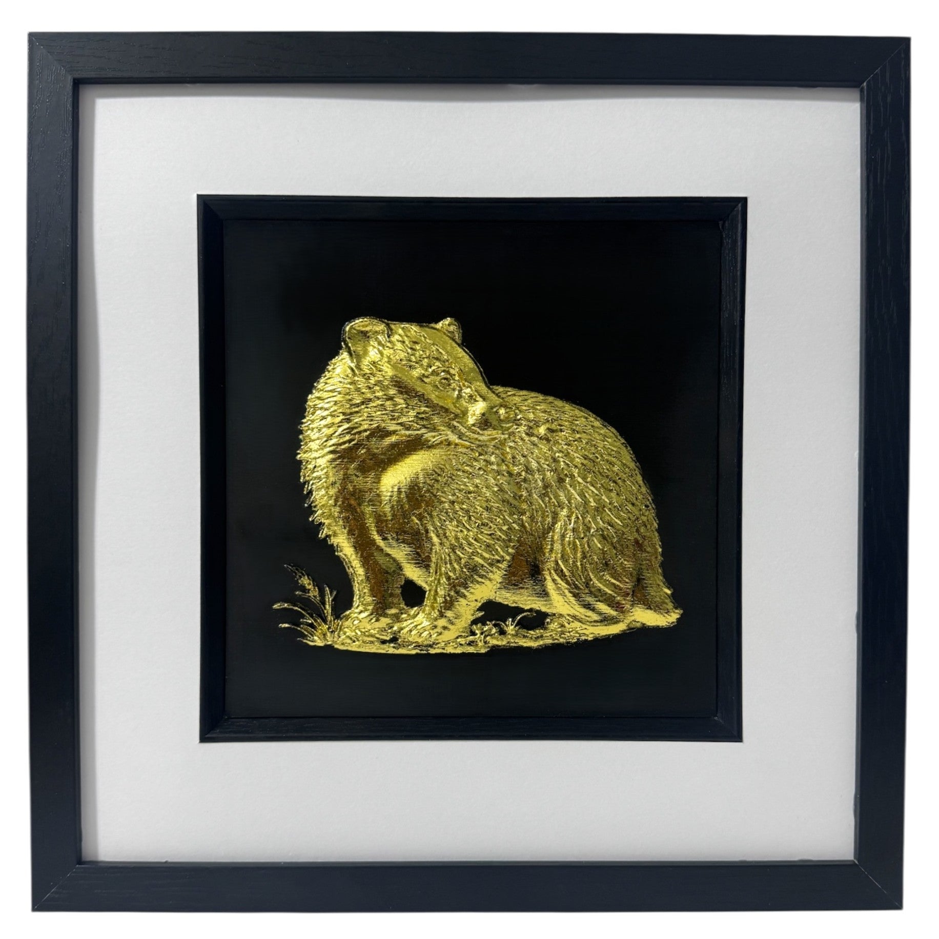 Framed 3D badger wall art finished in gold leaf. Handmade relief sculpture of a British badger on a black background.