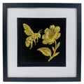Gold bee and flower wall art on black background with white mount