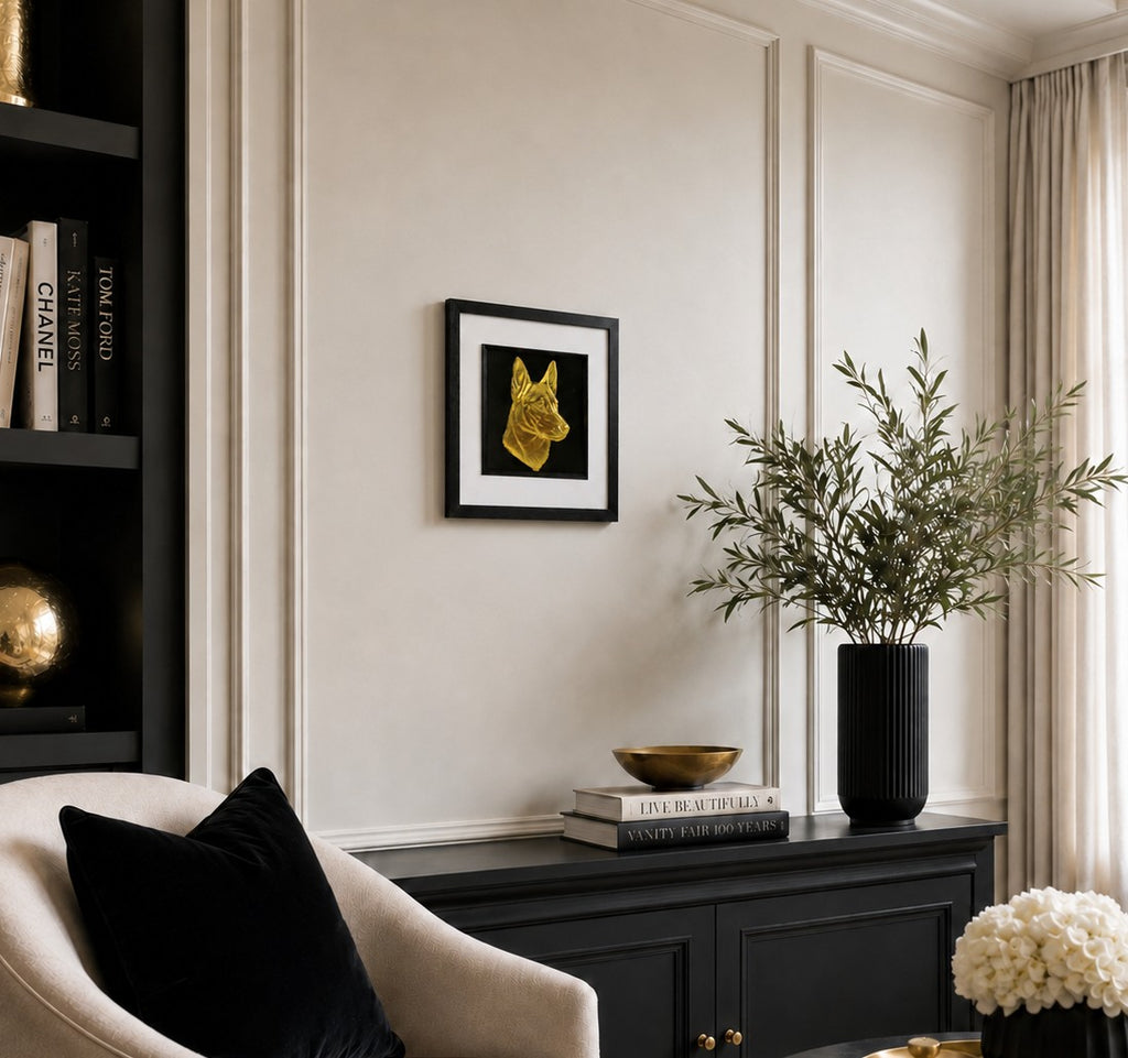 Angled lifestyle view of Belgian Malinois gold leaf framed wall art hanging on a neutral wall in a modern black, cream and gold interior.