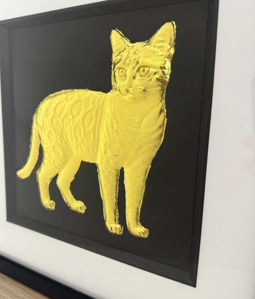 Close up of Bengal cat gold leaf relief detail on black background inside the frame