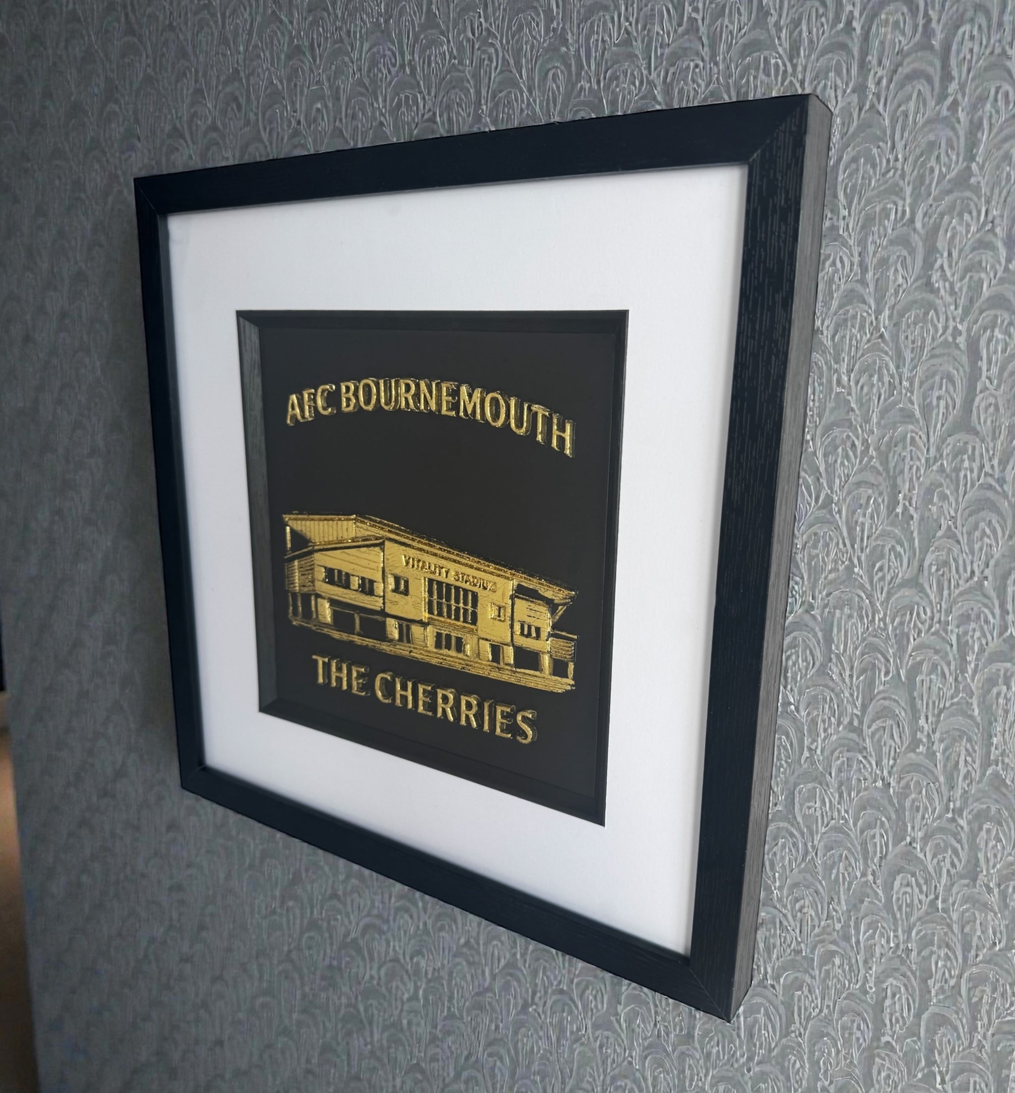 Framed AFC Bournemouth Vitality Stadium relief artwork in Gold or Silver Leaf style shown on a wall, black box frame with white mount and inner black surround