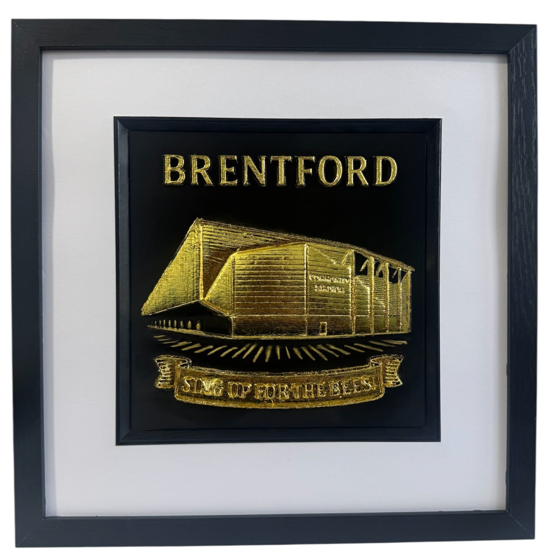 Gold Brentford stadium 3D relief artwork with “BRENTFORD” text and “SING UP FOR THE BEES” banner in black square frame with white mount, front view