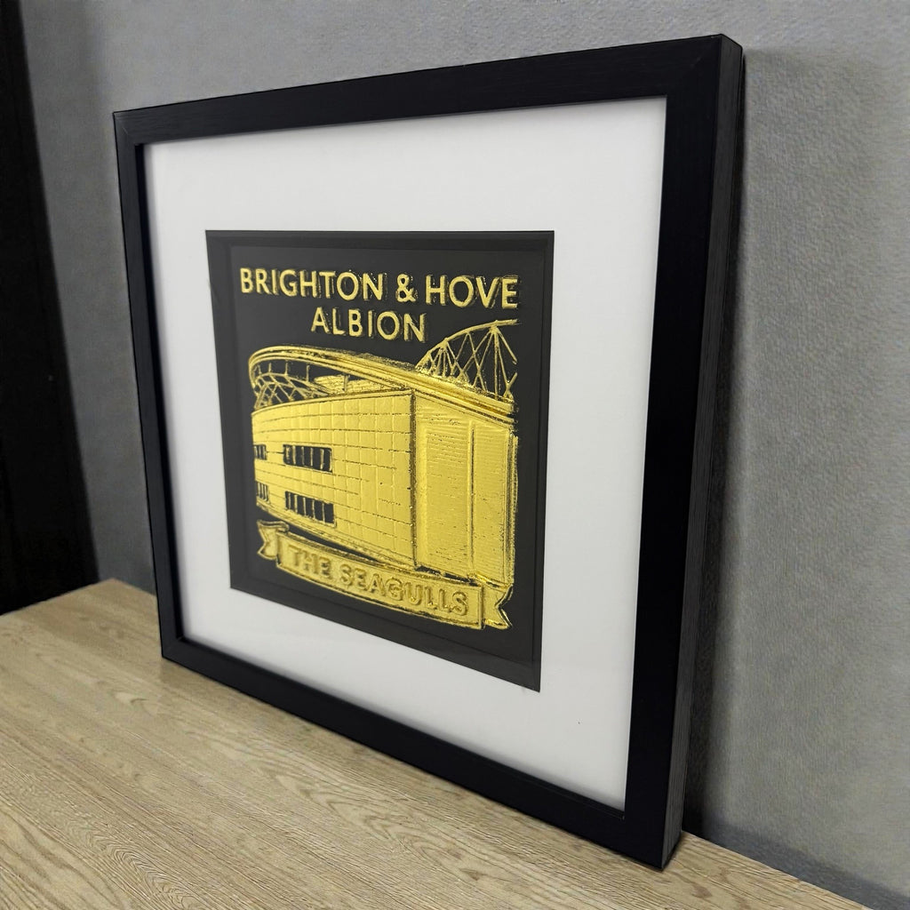 Brighton and Hove Albion Amex Stadium wall decor in gold leaf shown on a desk in a black frame