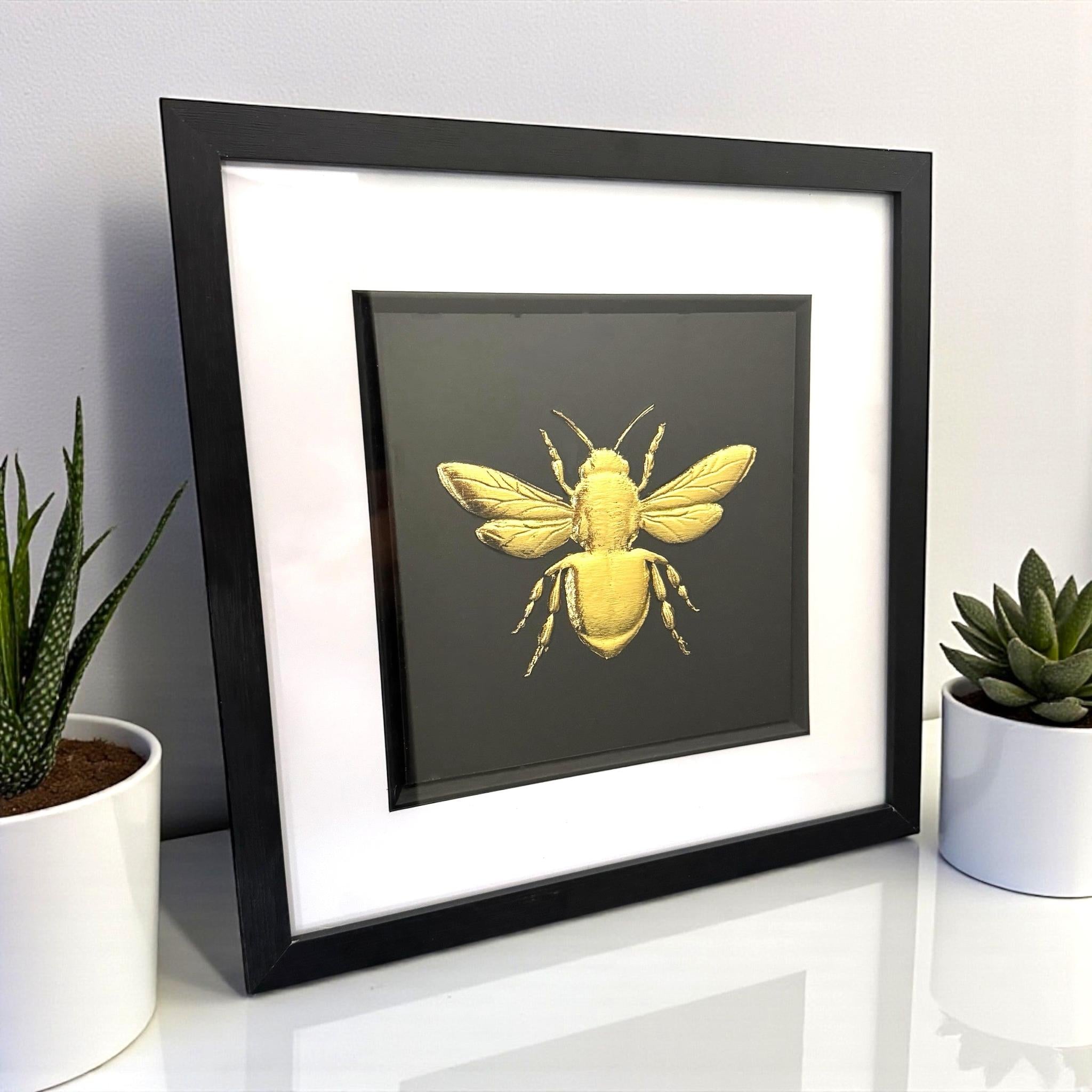 Angled view of gold leaf bumble bee framed artwork displayed on a shelf