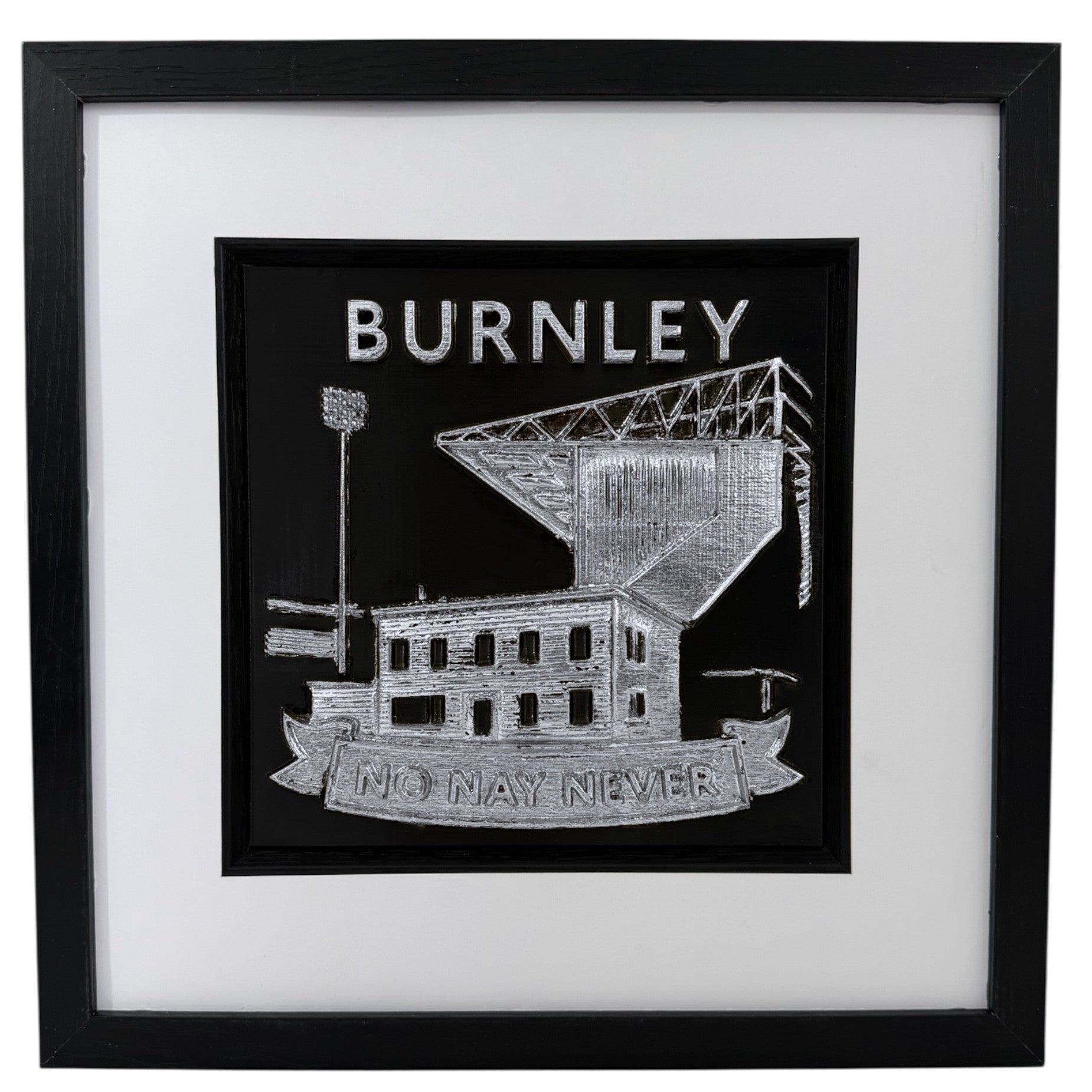 Front view of a silver Burnley football club relief in a black frame with wide white mount and black inner surround.