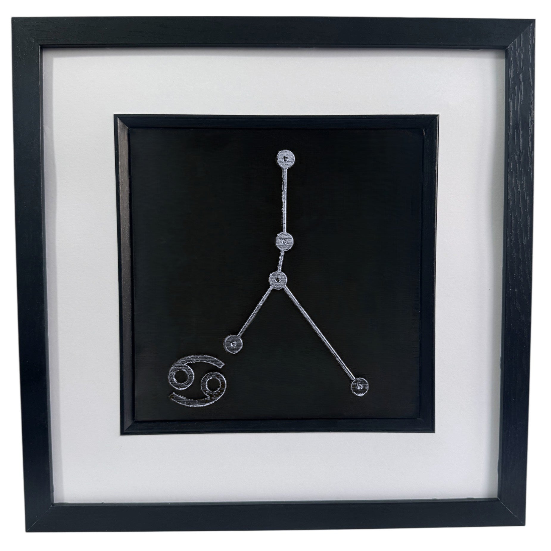 Framed Cancer constellation wall art in silver leaf with star pattern and zodiac symbol, centred on a black background with white mount and black frame