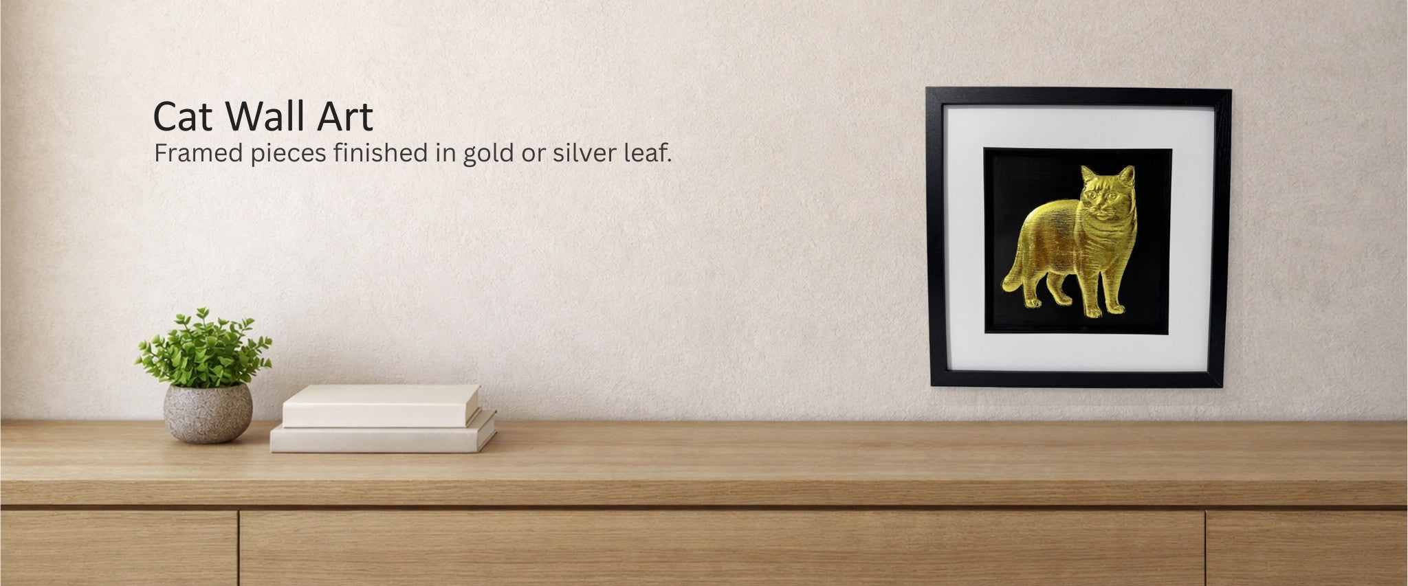Cat wall art collection banner showing a gold cat relief in a black square frame with white mount on a textured beige wall above a light oak console, JP Designs.