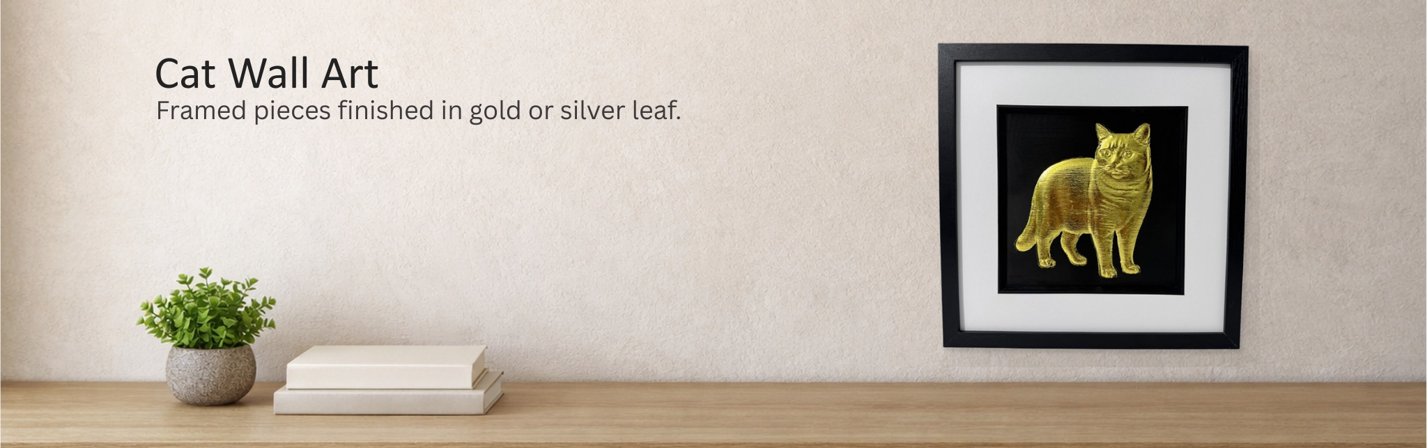 Cat wall art collection banner showing a gold cat relief in a black square frame with white mount on a textured beige wall above a light oak console, JP Designs.