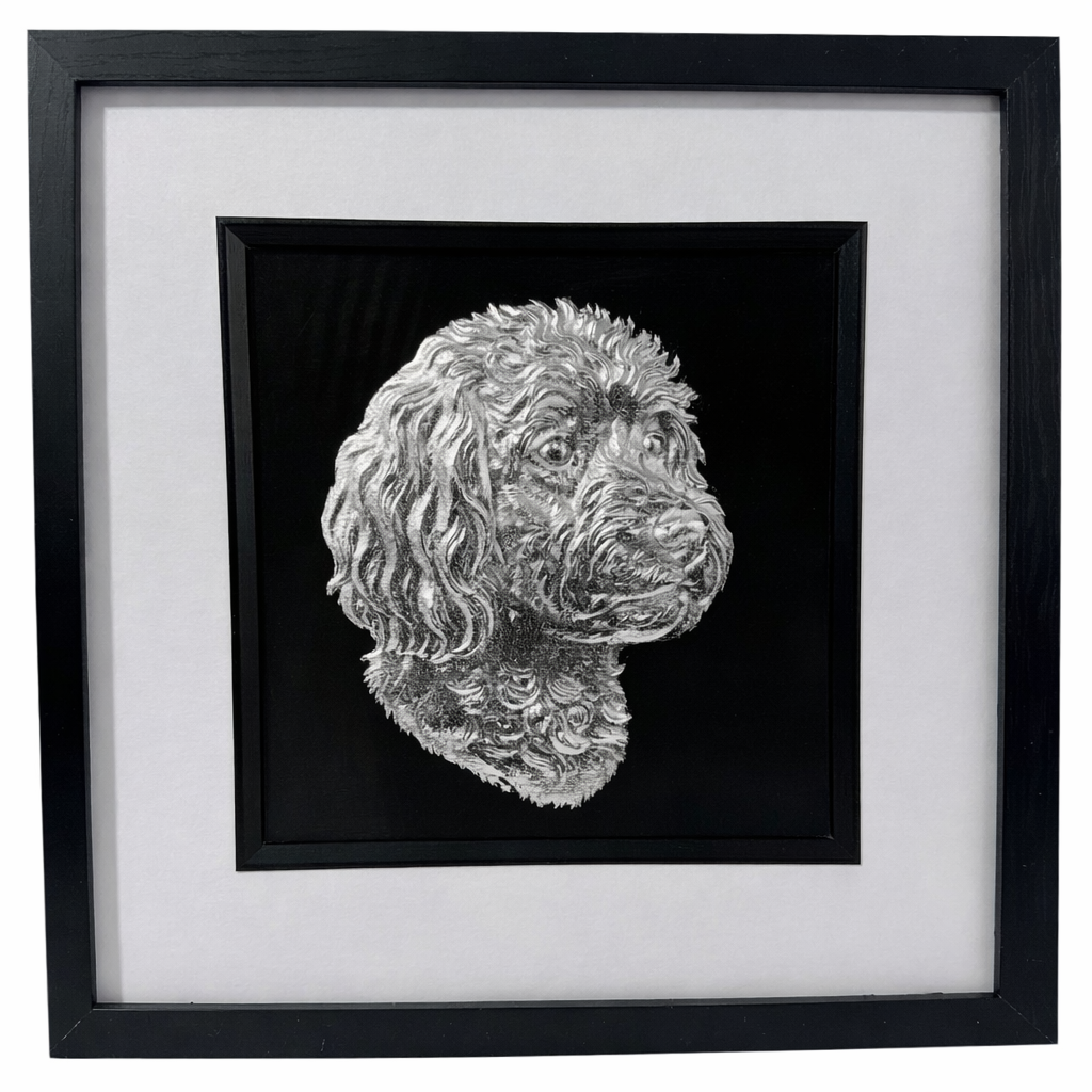 Framed cavapoo wall art with silver relief portrait on a black background, set in a black frame with white mount on a clean white background