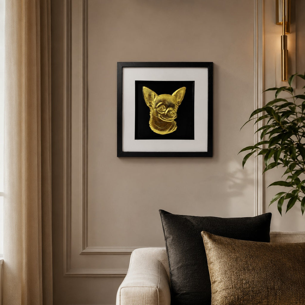 Chihuahua gold leaf framed dog wall art displayed above a cream sofa in a warm neutral living room with black and gold accents.