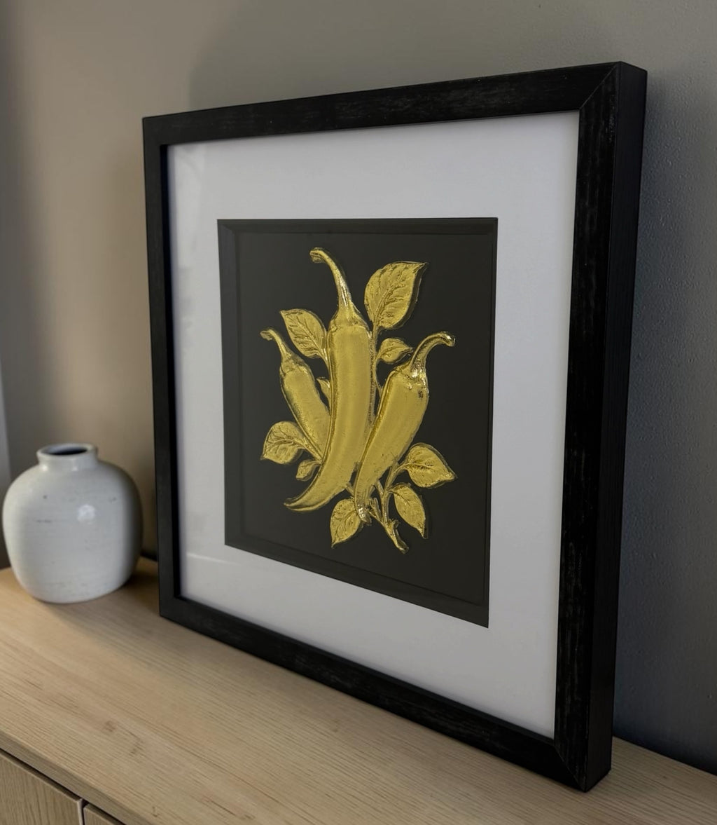 Gold chilli pepper framed 3D artwork styled on a sideboard with ceramic vase and neutral wall.