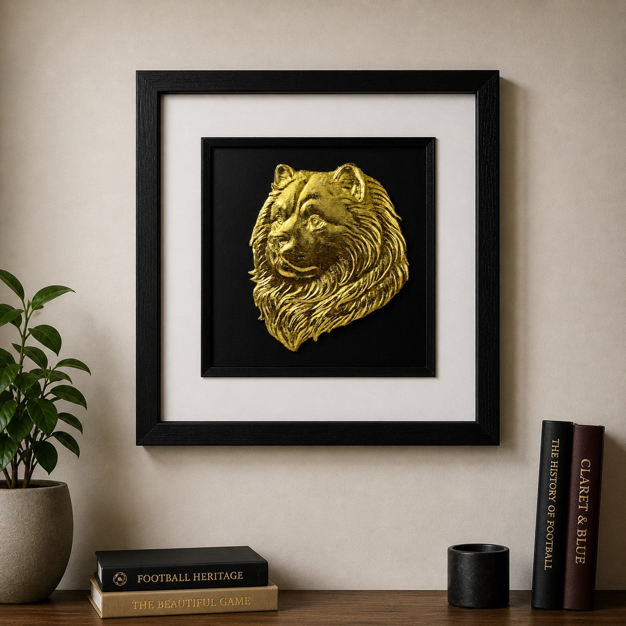 Gold Chow Chow wall art in a black square frame styled above a wooden console with football books, plant decor and neutral home interiors.