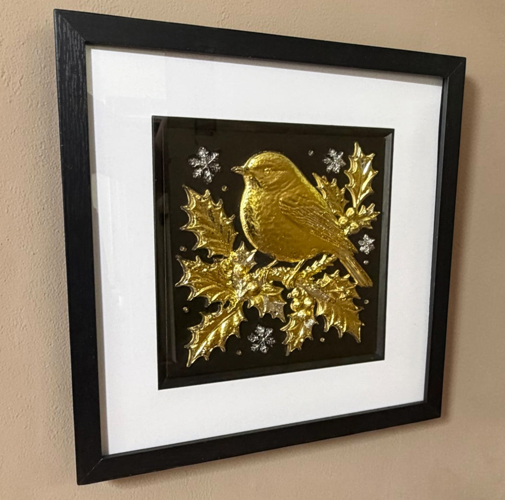 Gold and silver Christmas robin 3D wall art hanging on a beige textured wall, viewed from the side to show the depth of the black box frame and the raised holly
