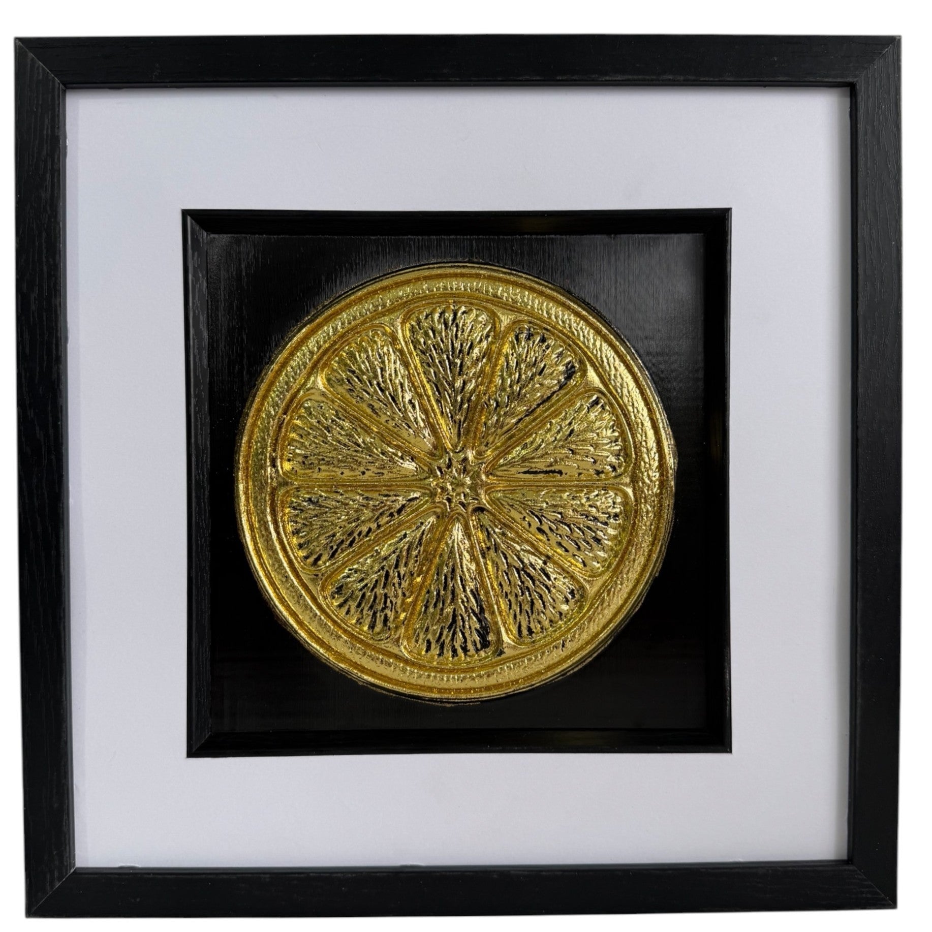 Straight-on Gold orange slice relief artwork with segmented citrus detail, black background and white mount.