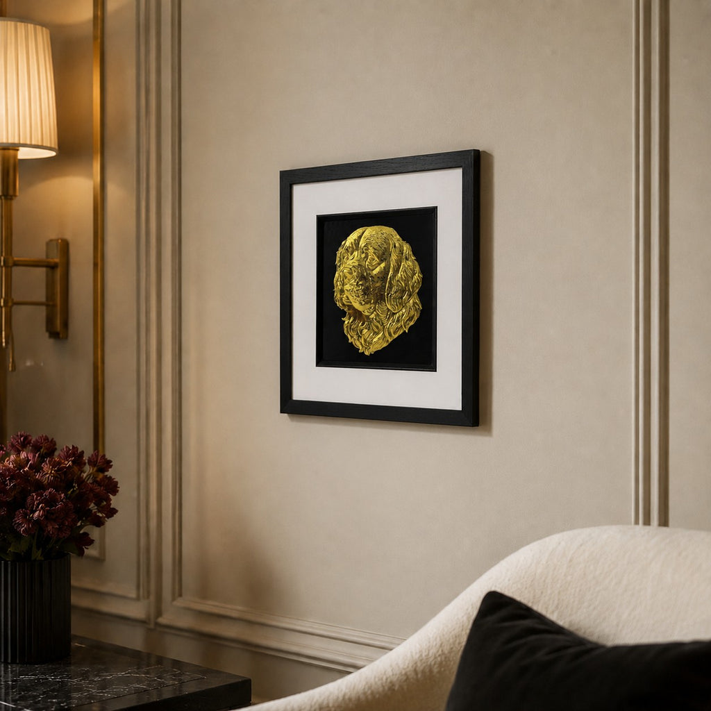 Angled lifestyle view of Clumber Spaniel gold 3D relief dog wall art in a black frame with white mount on a luxury neutral wall.