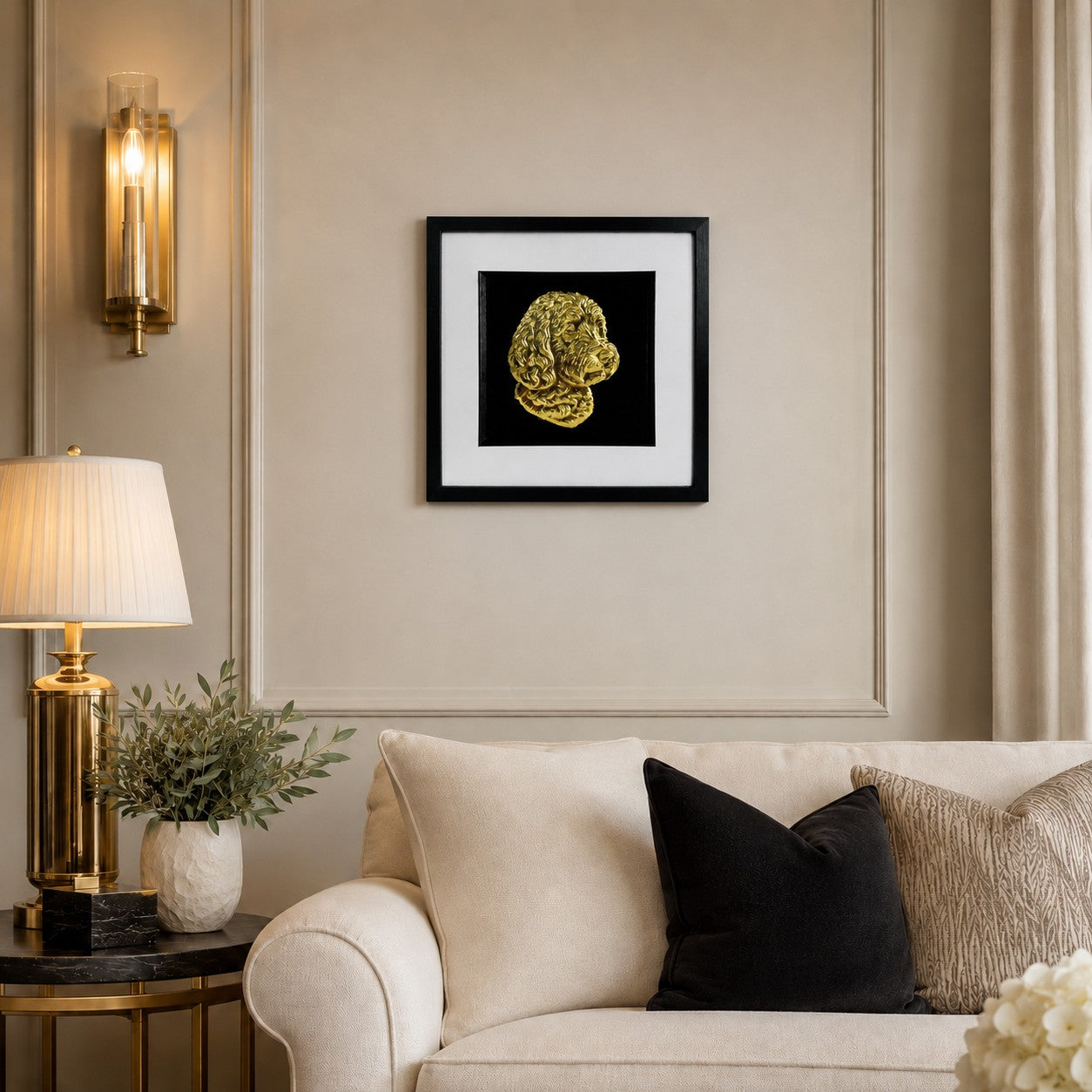 Cockapoo gold leaf framed dog wall art displayed above a cream sofa in a warm neutral living room with black and gold accents.