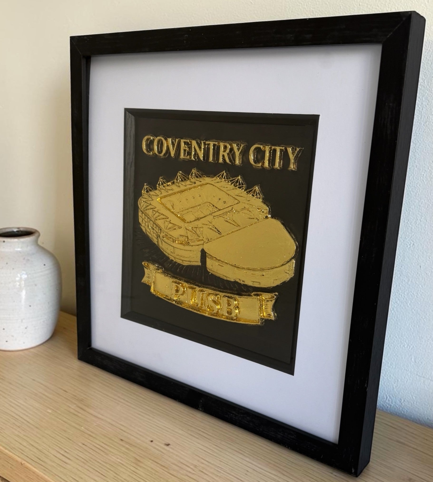 Gold Coventry City stadium framed 3D relief art shown at an angle in a black square frame with white mount