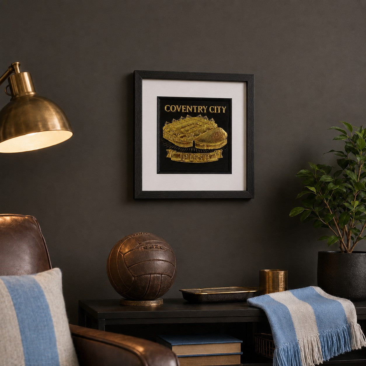 Gold Coventry City stadium framed artwork styled in a dark football room with lamp, chair, football and plan