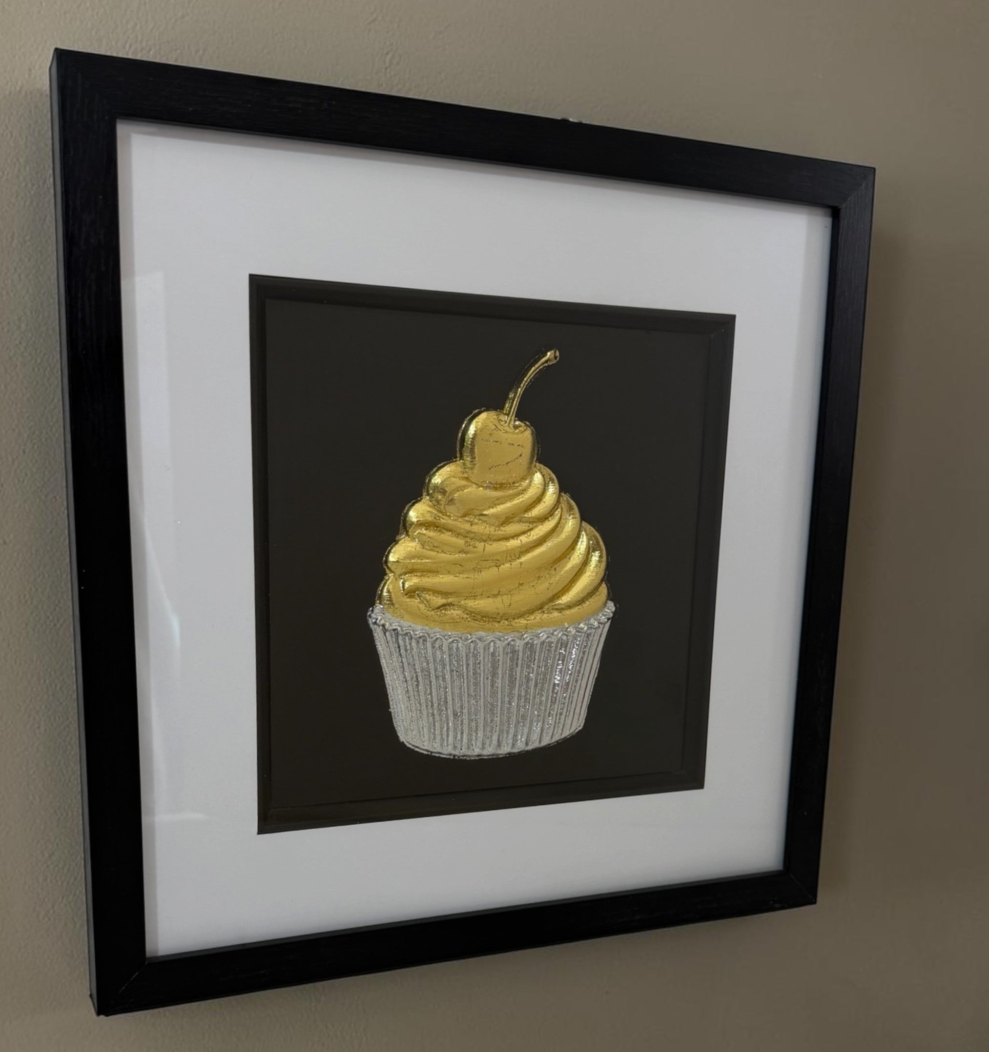 Angled cupcake framed artwork showing raised gold and silver relief detail through the glass front.