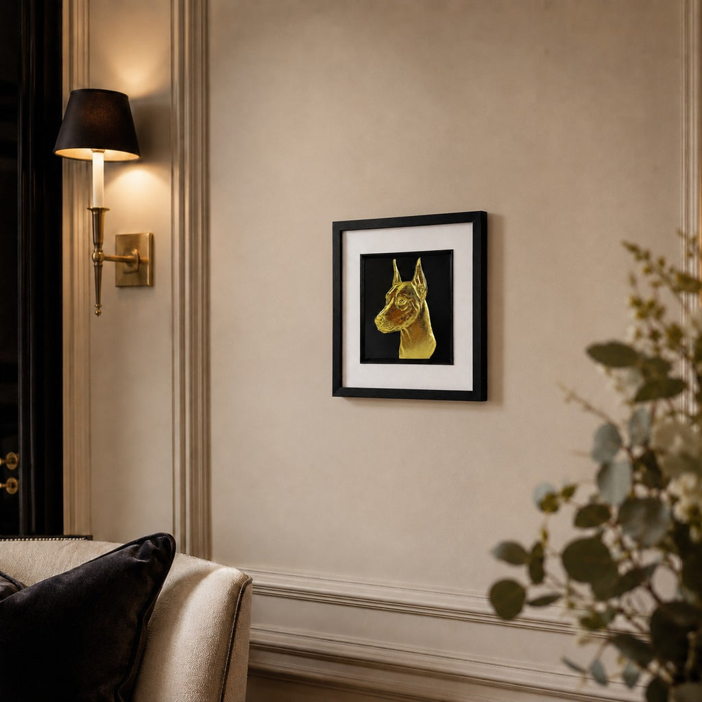 Angled lifestyle view of Doberman gold 3D relief dog wall art in a black frame with white mount on a warm neutral wall.