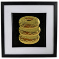 Straight-on Gold doughnut stack relief artwork with black centre panel, white mount and black frame.