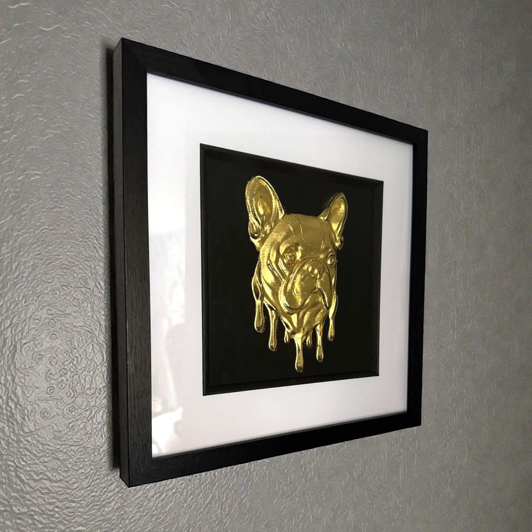 Molten French Bulldog gold leaf framed wall art mounted on a wall shown at an angle with black frame and white mount
