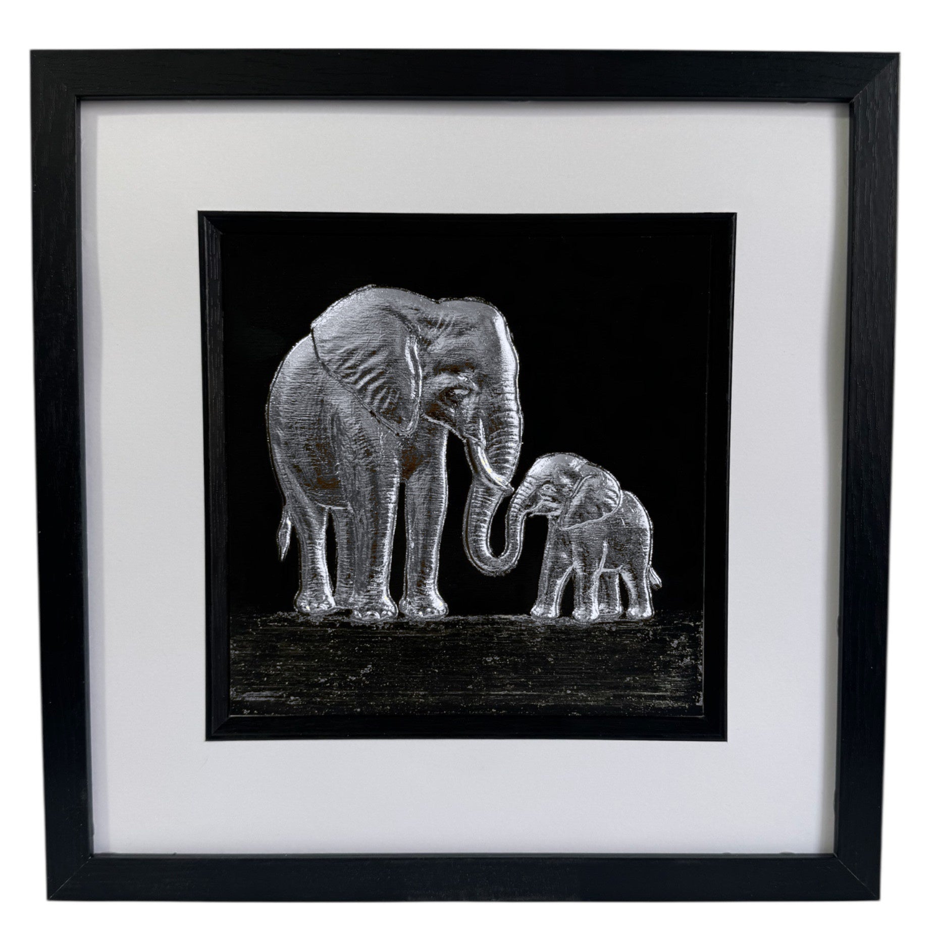 Framed elephant mother and baby wall art in silver leaf relief on a black background with white mount and black frame