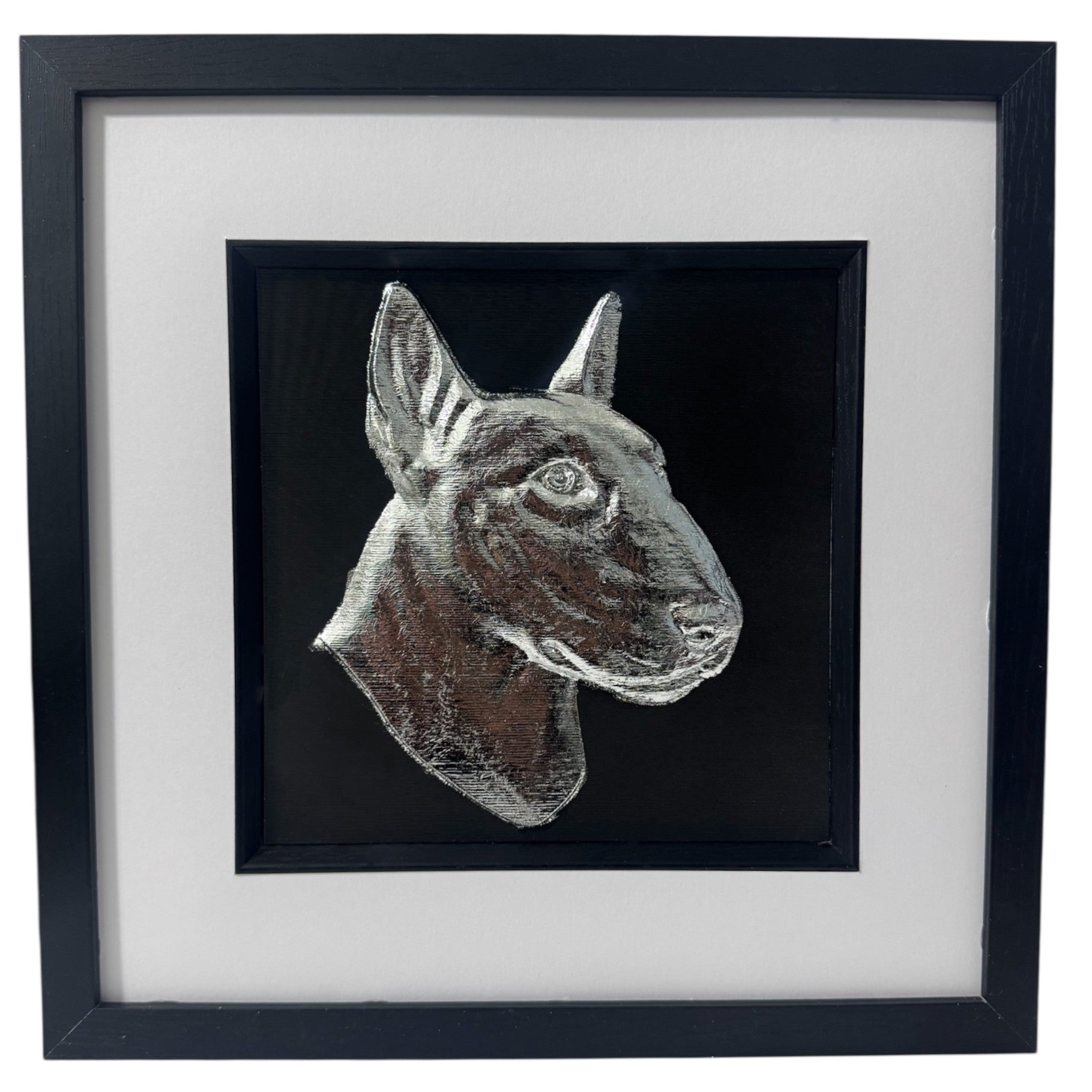 English Bull Terrier framed wall art showing a sculpted dog portrait in silver leaf, set on a black background with white mount and black wooden frame
