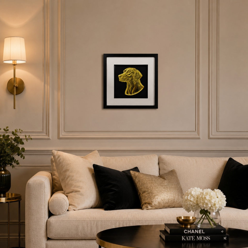 English Pointer gold leaf framed dog wall art displayed above a cream sofa in a warm neutral living room with black and gold accents.