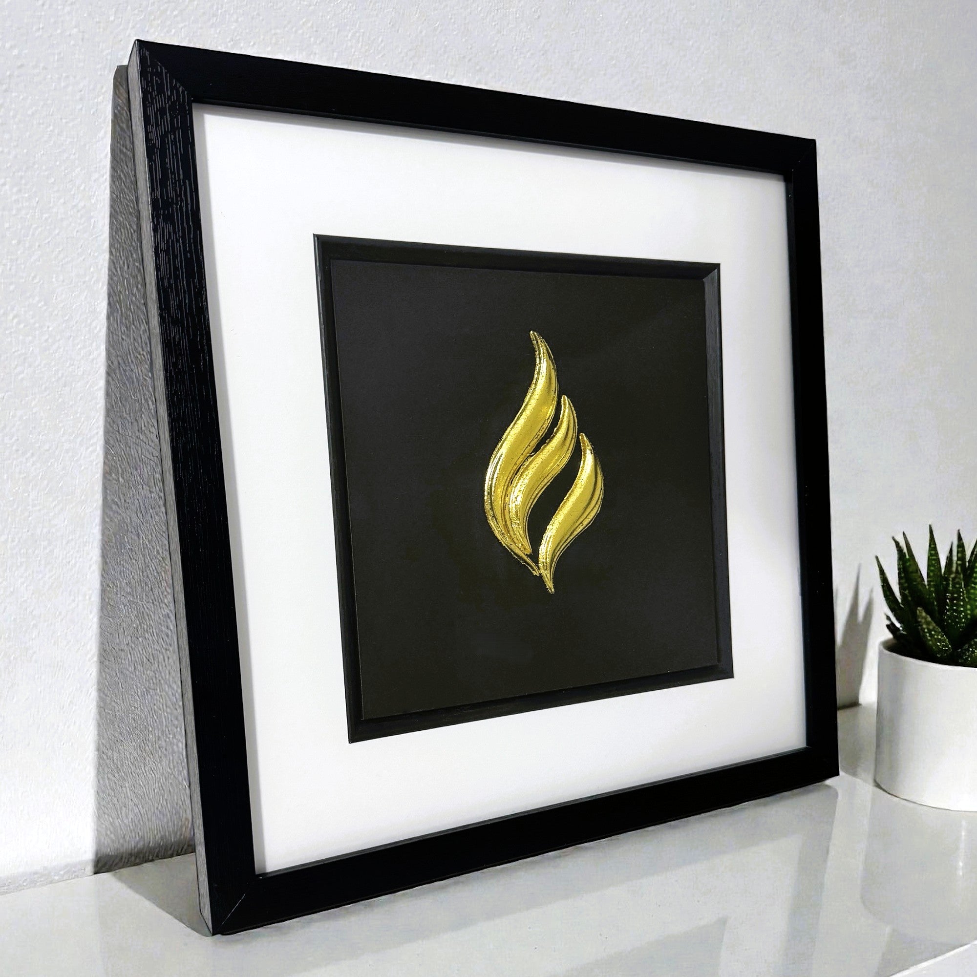 Eternal flame gold leaf framed wall art shown at an angle on a modern interior surface