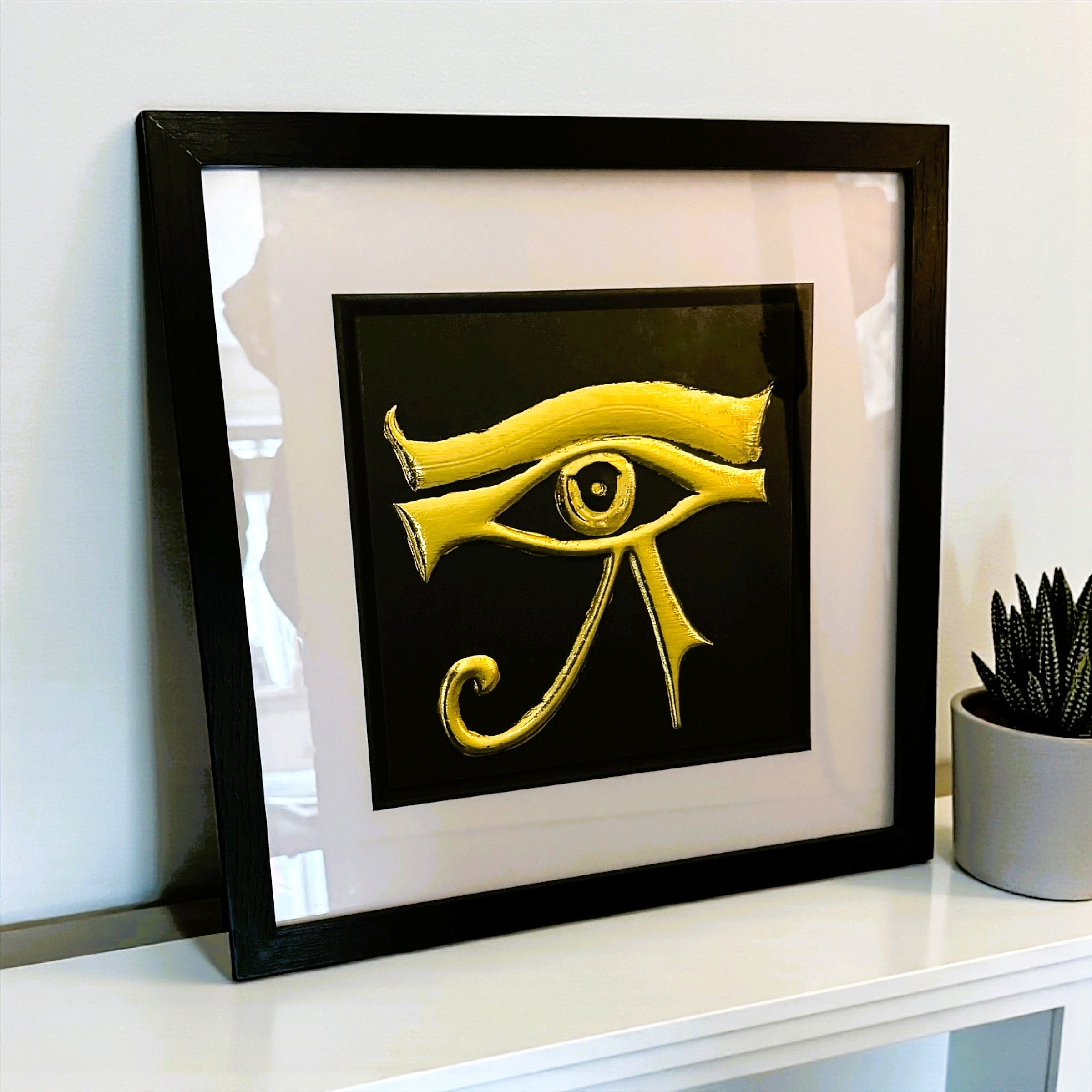 Angled desk view of Eye of Horus wall art displayed on a white surface