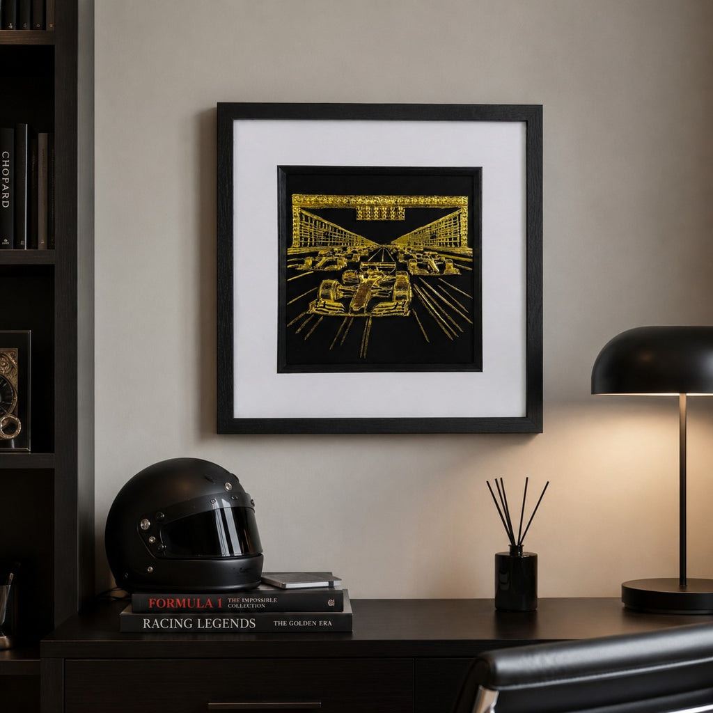 A gold leaf Formula 1 framed art piece hanging above a blue armchair, showing how the metallic finish catches the light in a modern living room.
