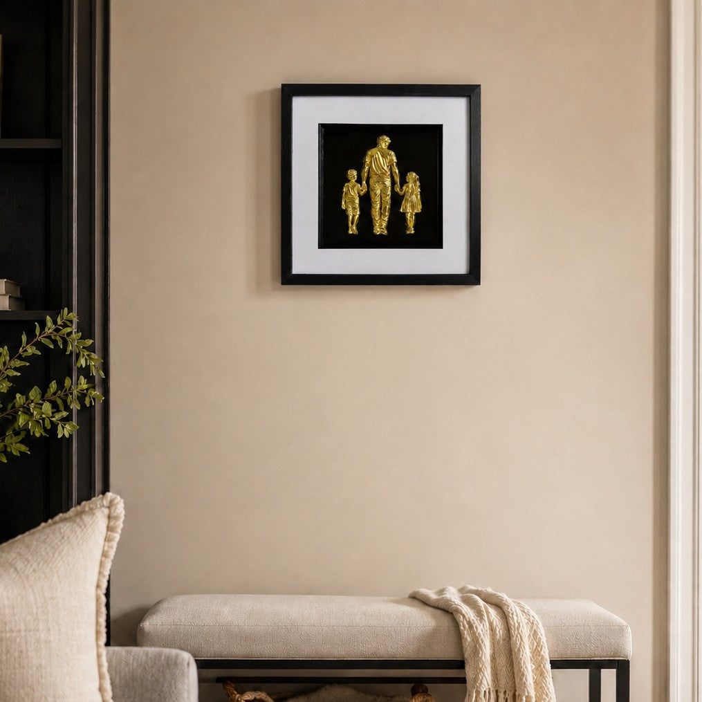 Gold father and children framed artwork styled above a bench in a neutral hallway or living room.