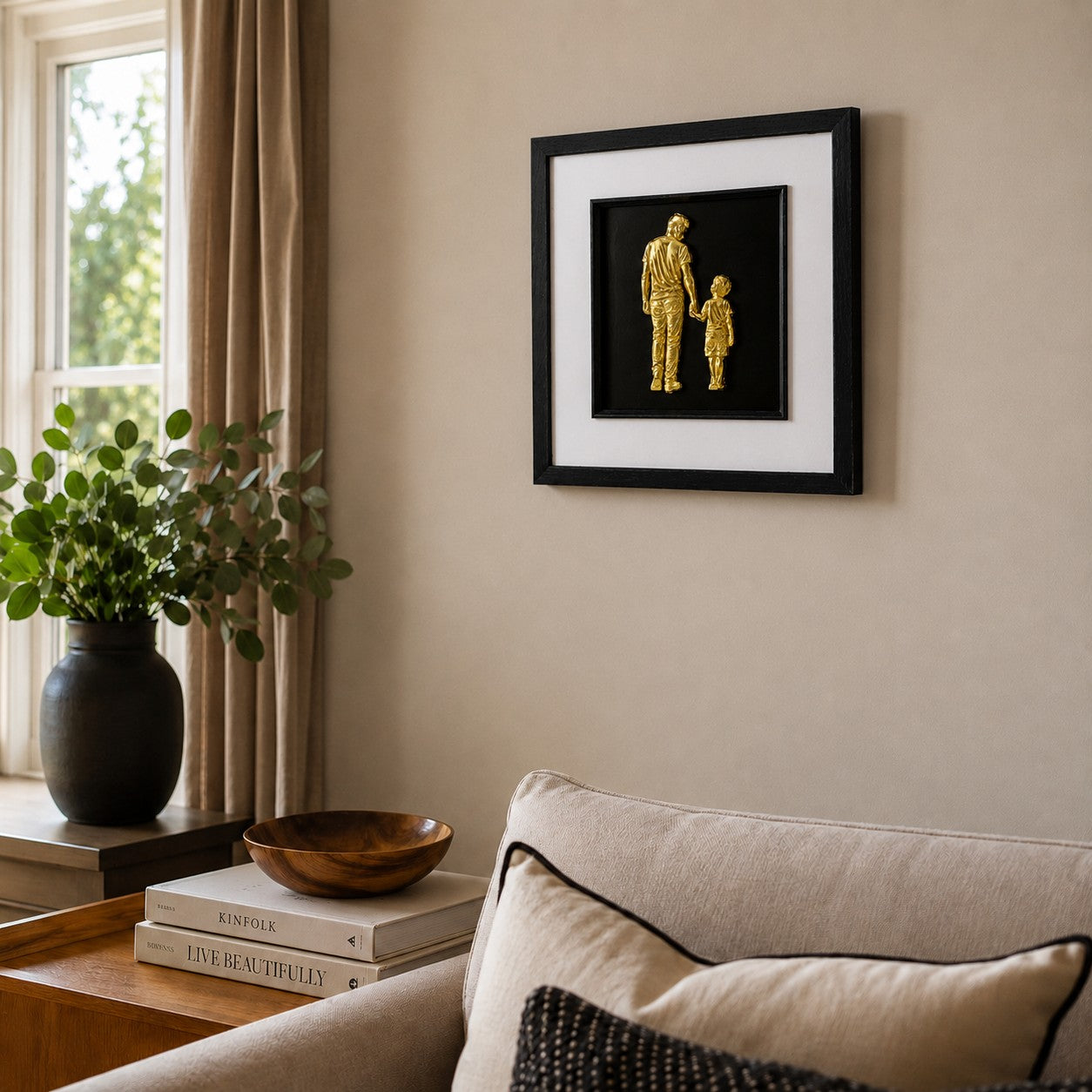Gold father and son framed artwork styled in a warm living room above a sofa with neutral cushions.