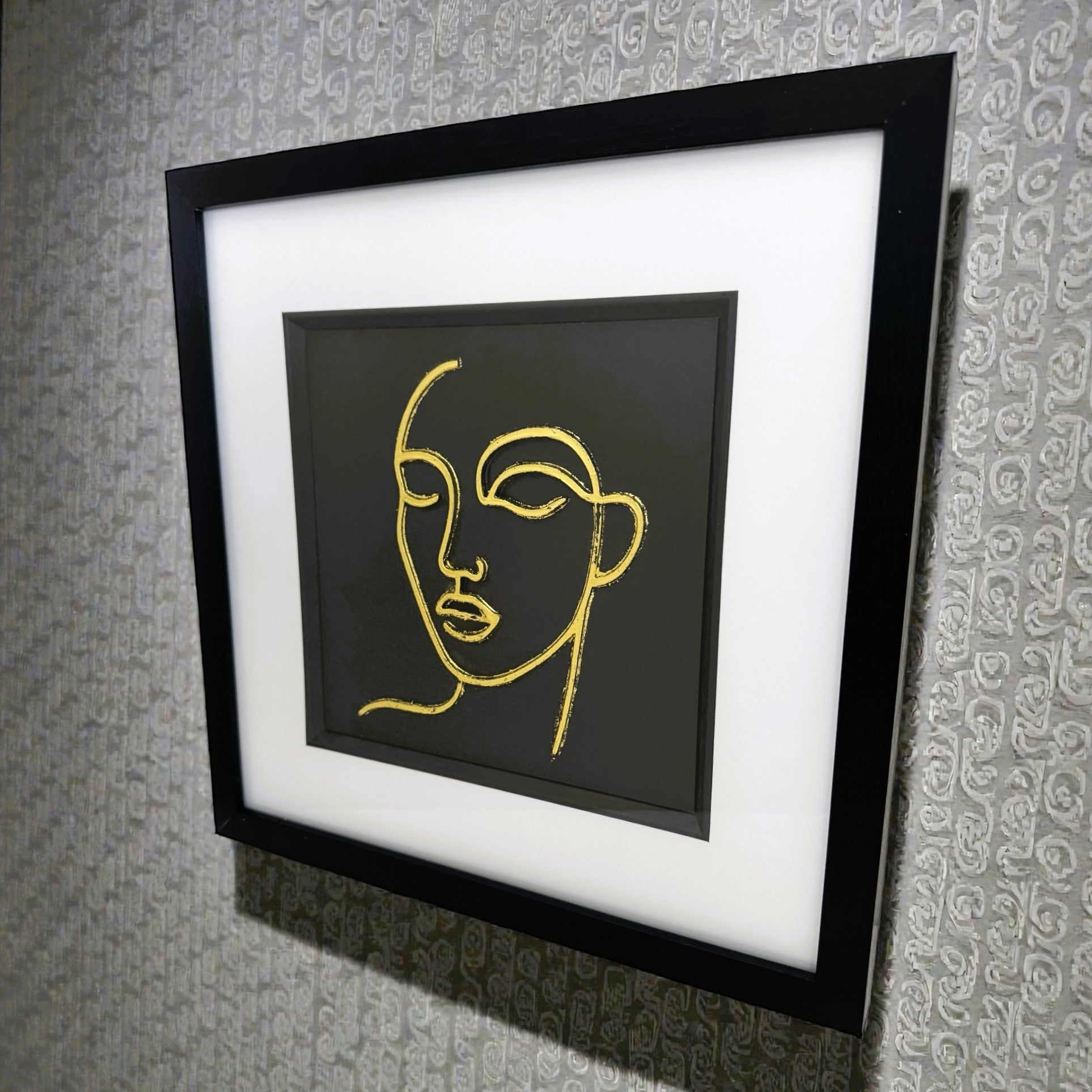 Angled view of gold leaf female line art wall art displayed on wall
